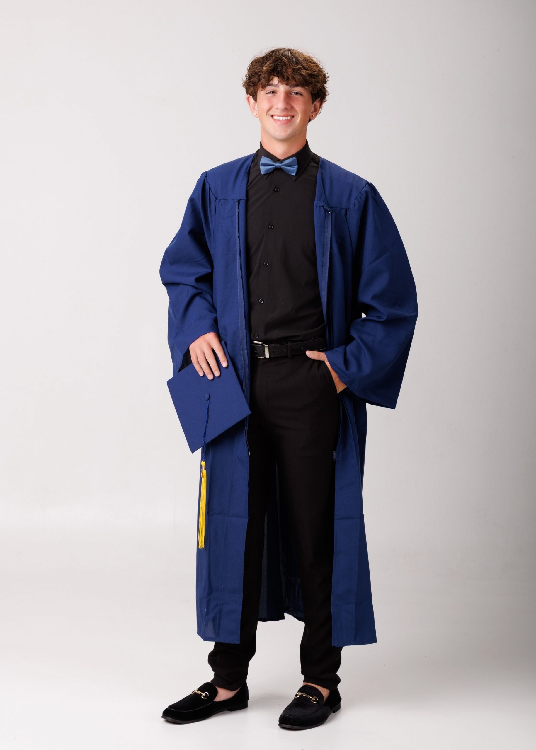 Cabrini Senior Jace wearing graduation gown with cap and tassel, standing confidently
