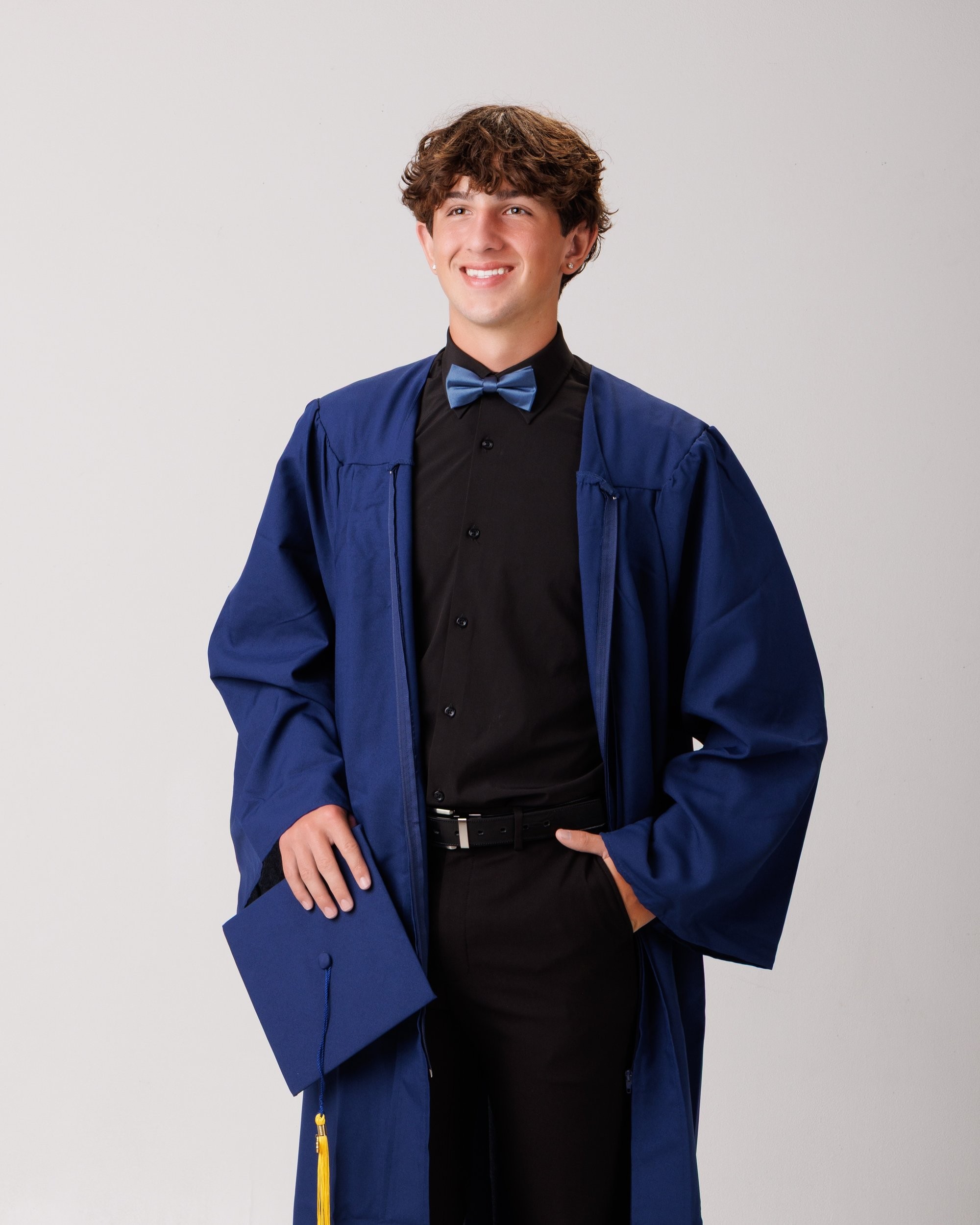 Cabrini Senior Jace posing in formal attire with graduation elements