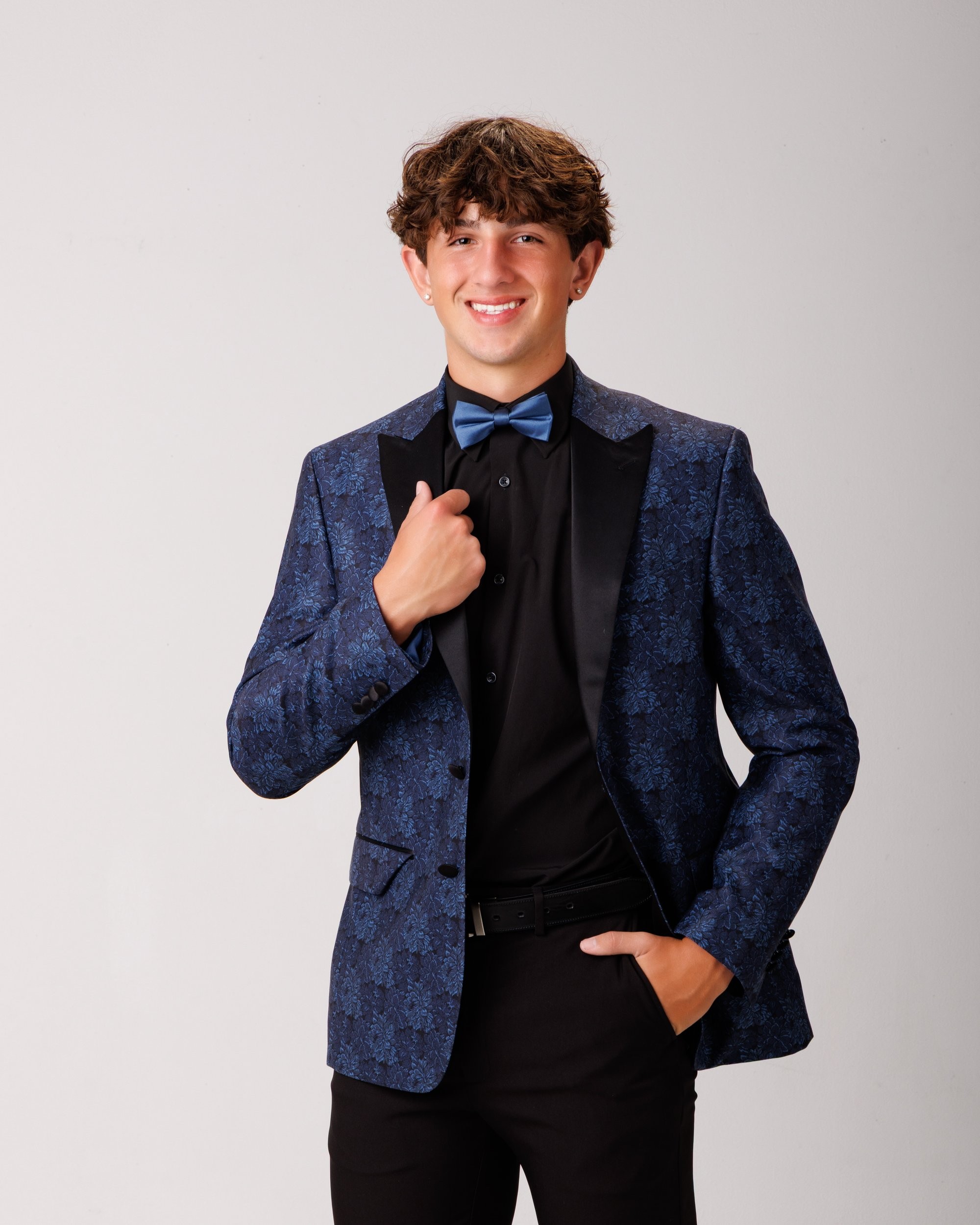 Cabrini Senior Jace posing in formal attire with graduation elements