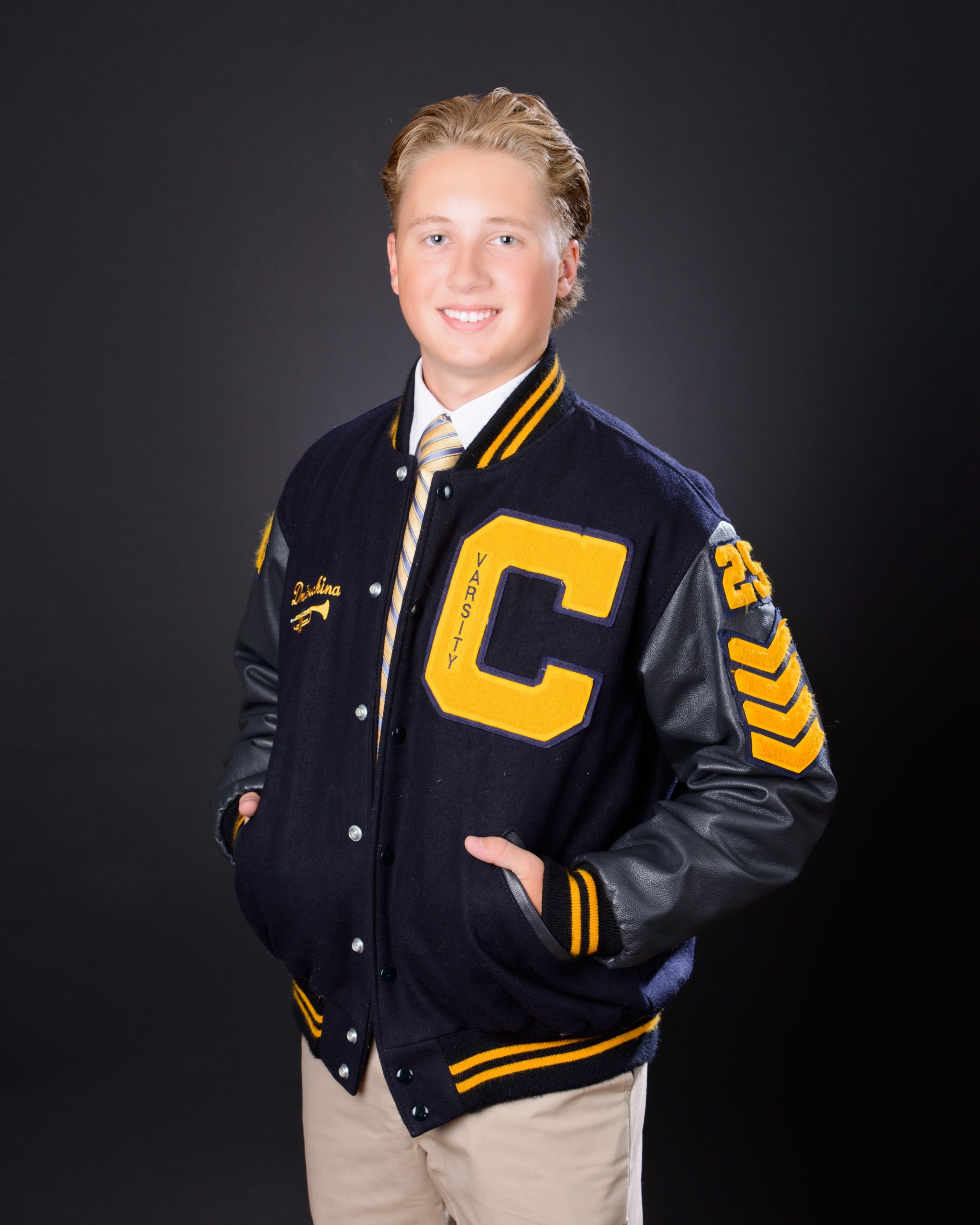 Matt in Cabrini varsity jacket, hands in pockets, senior photography