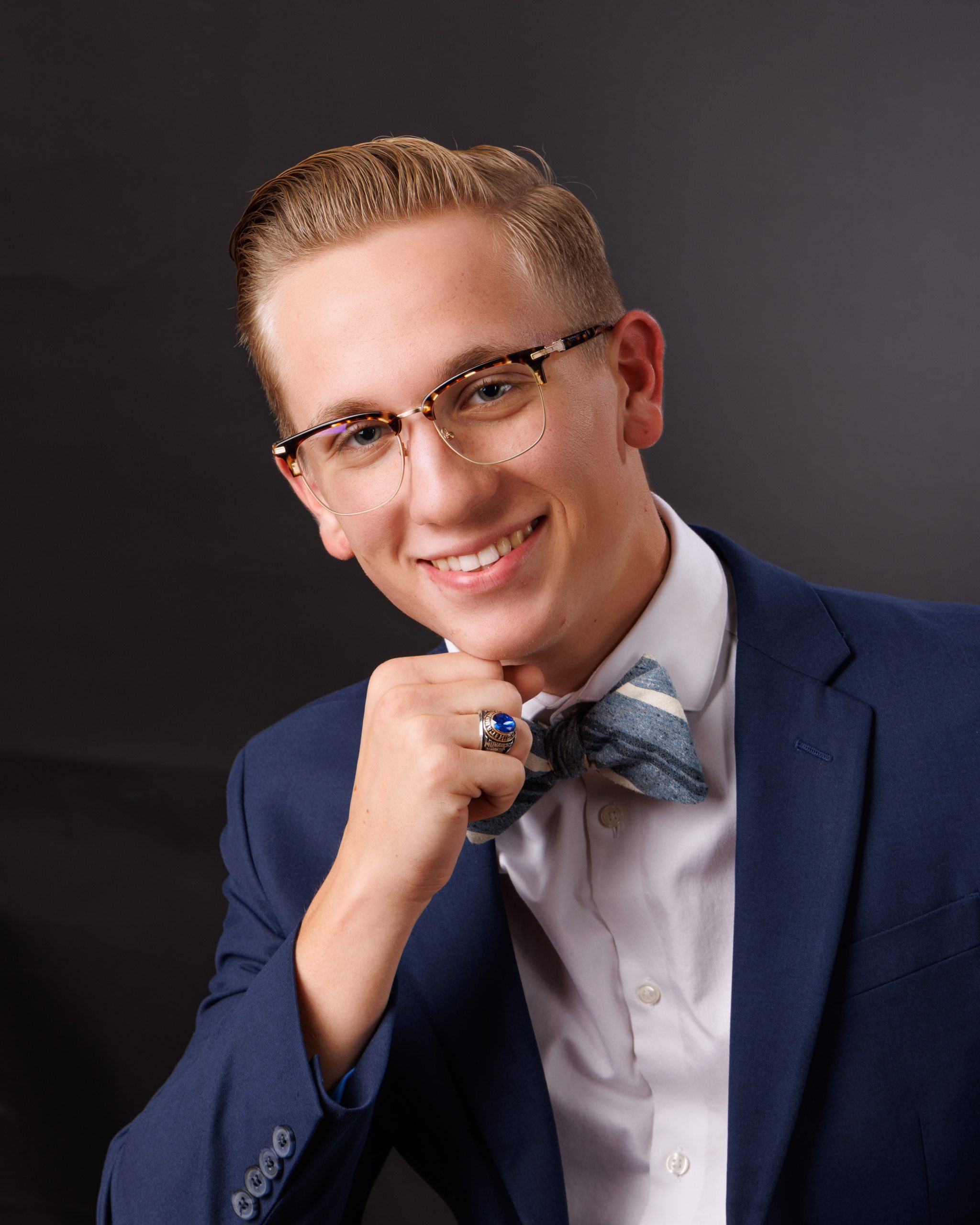 Formal senior photograph featuring Ralph in navy suit and striped bow tie, posing confidently