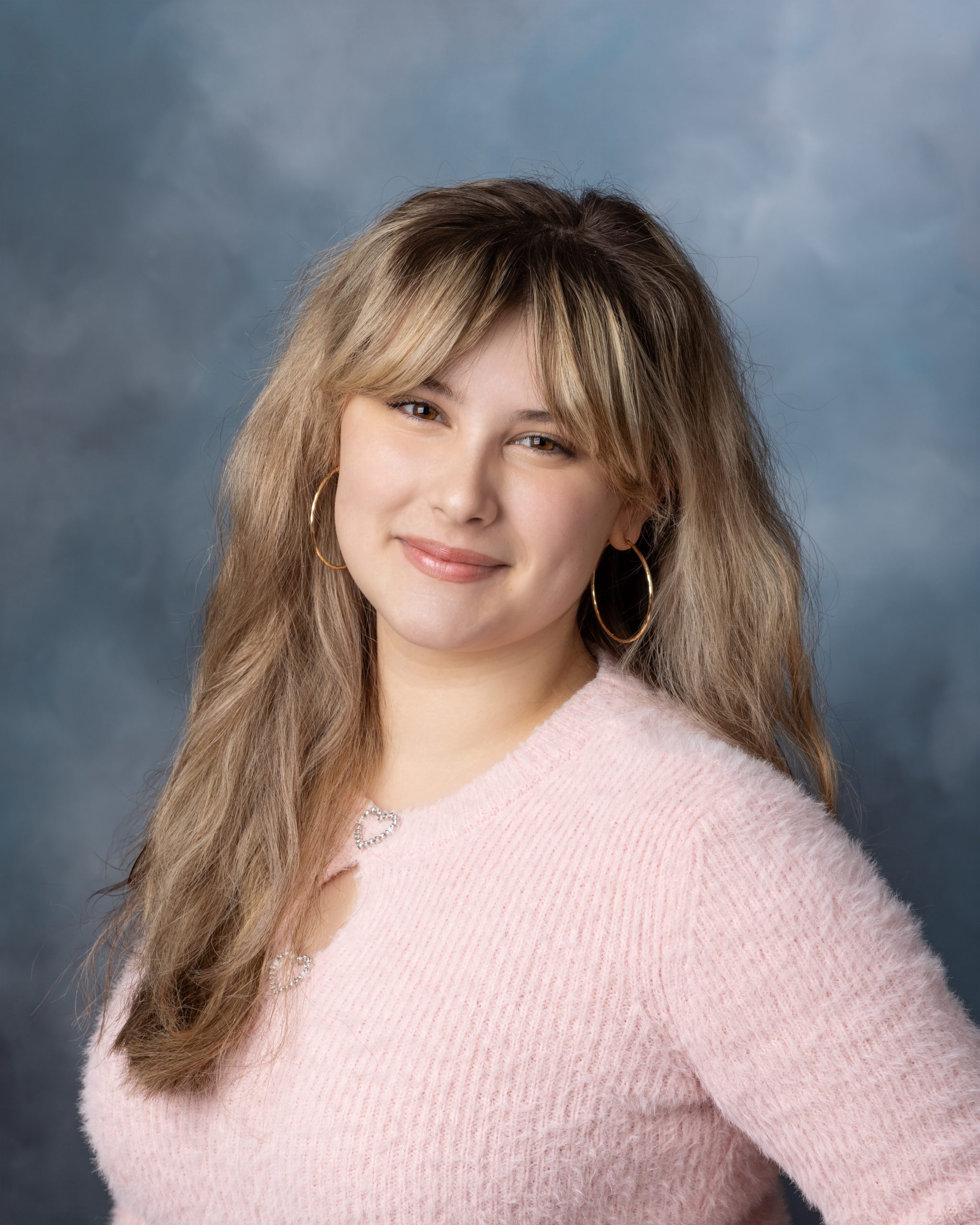 Female student in soft pink sweater with long hair for Cabrini senior yearbook photo