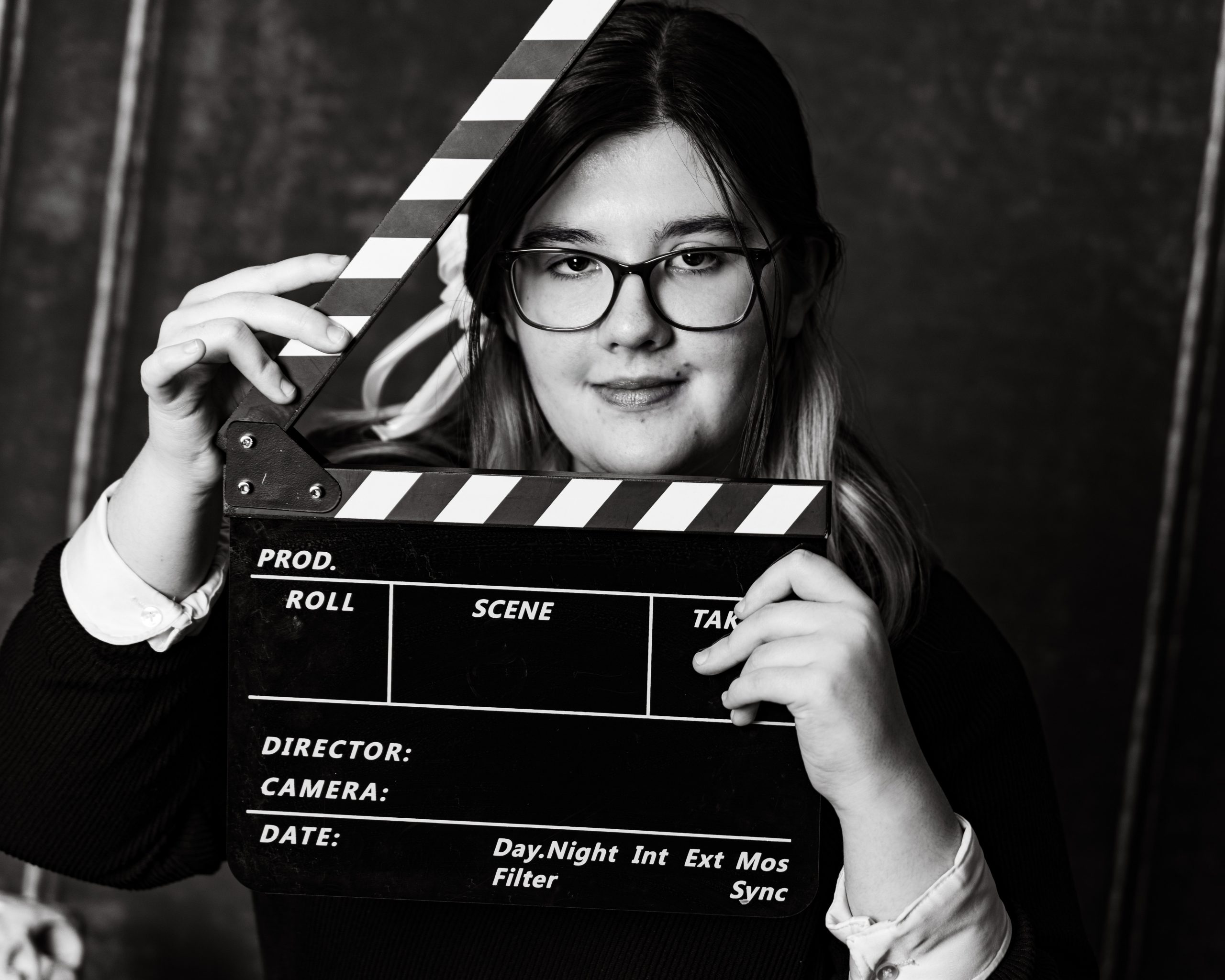 Kaitlyn holding a clapperboard during her creative senior photography session at Studio ONE
