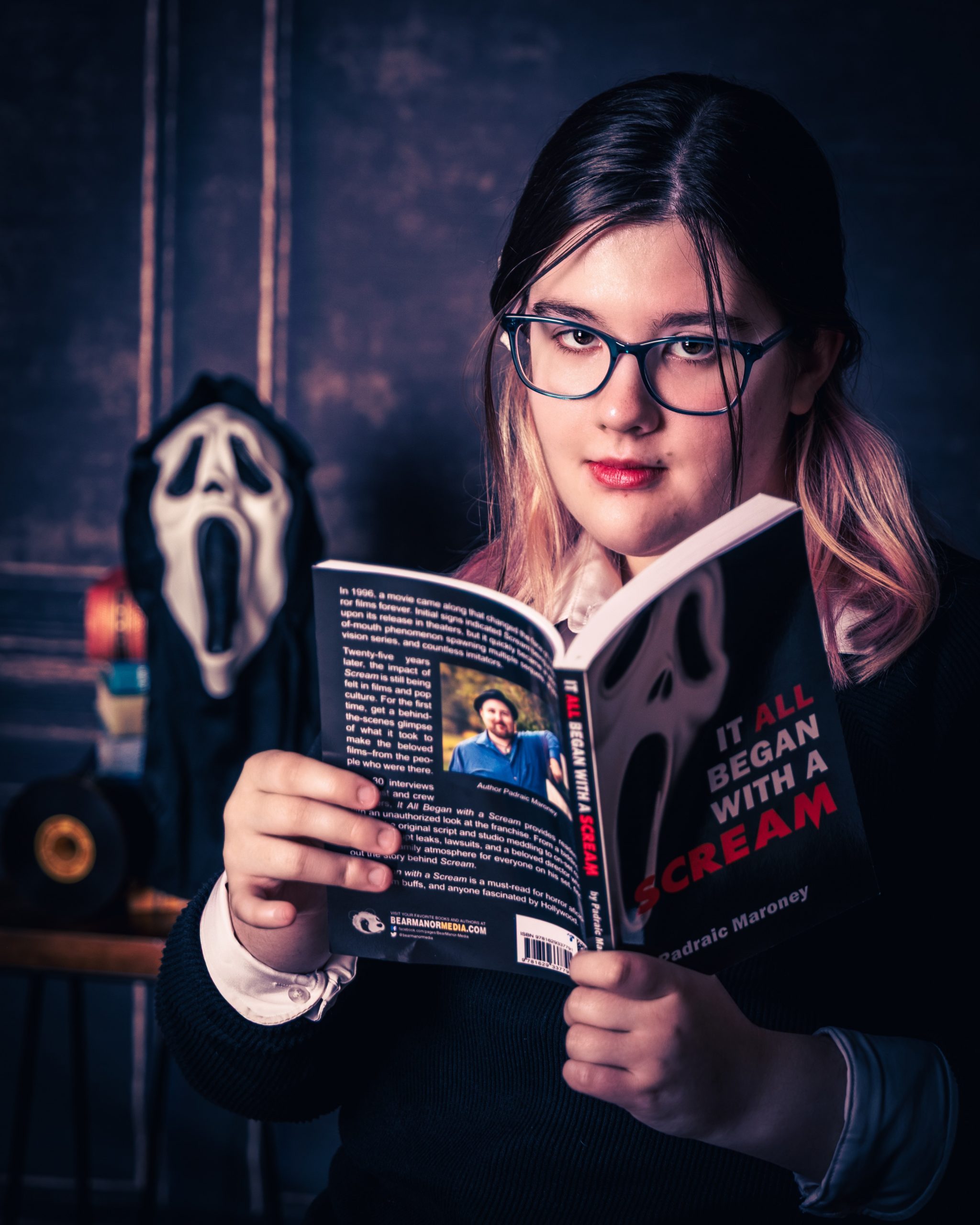 Kaitlyn posing with horror-themed props including a knife and book in a studio setup for her Canton Plymouth senior session