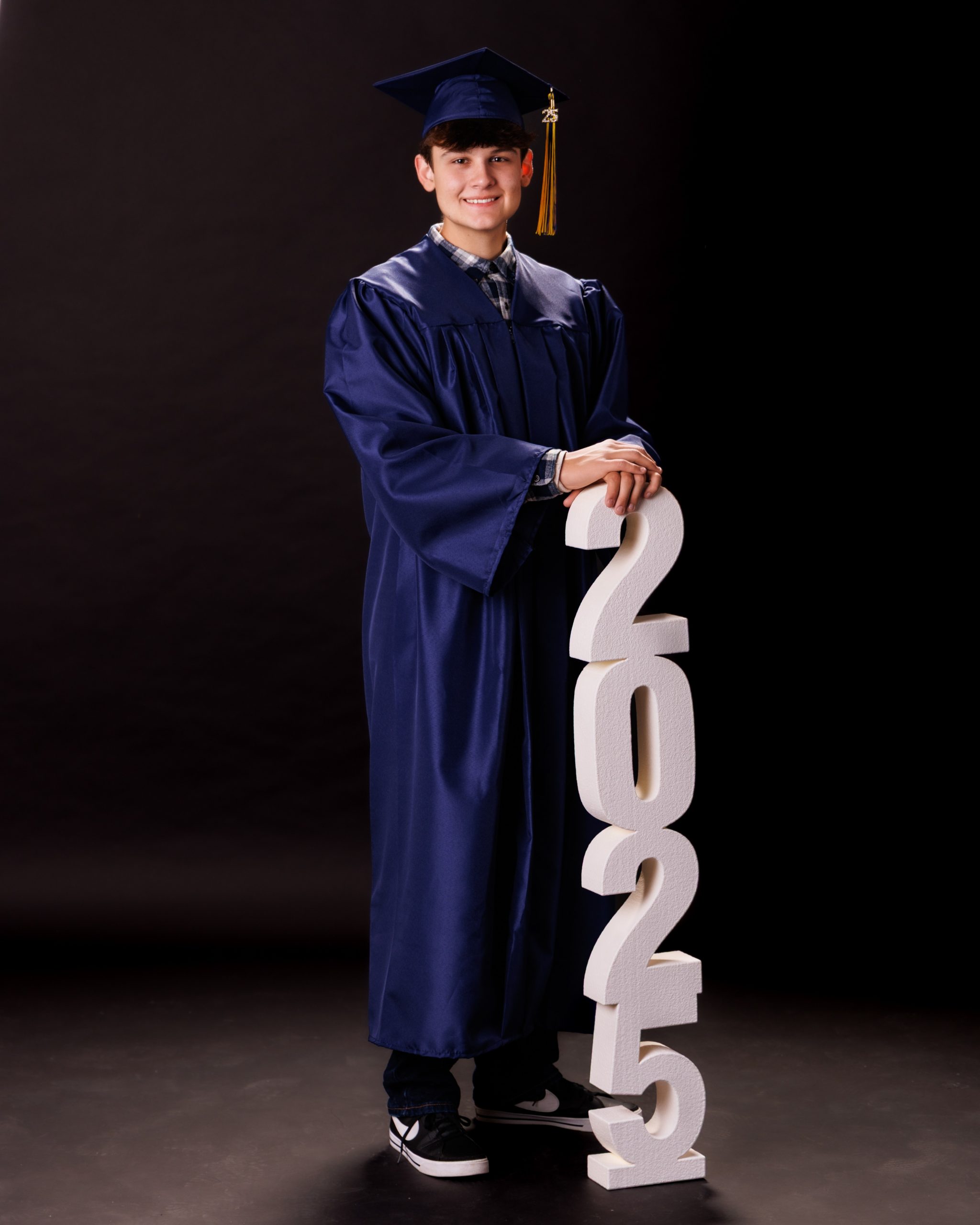 Close-up headshot of Andrew wearing graduation cap and gown