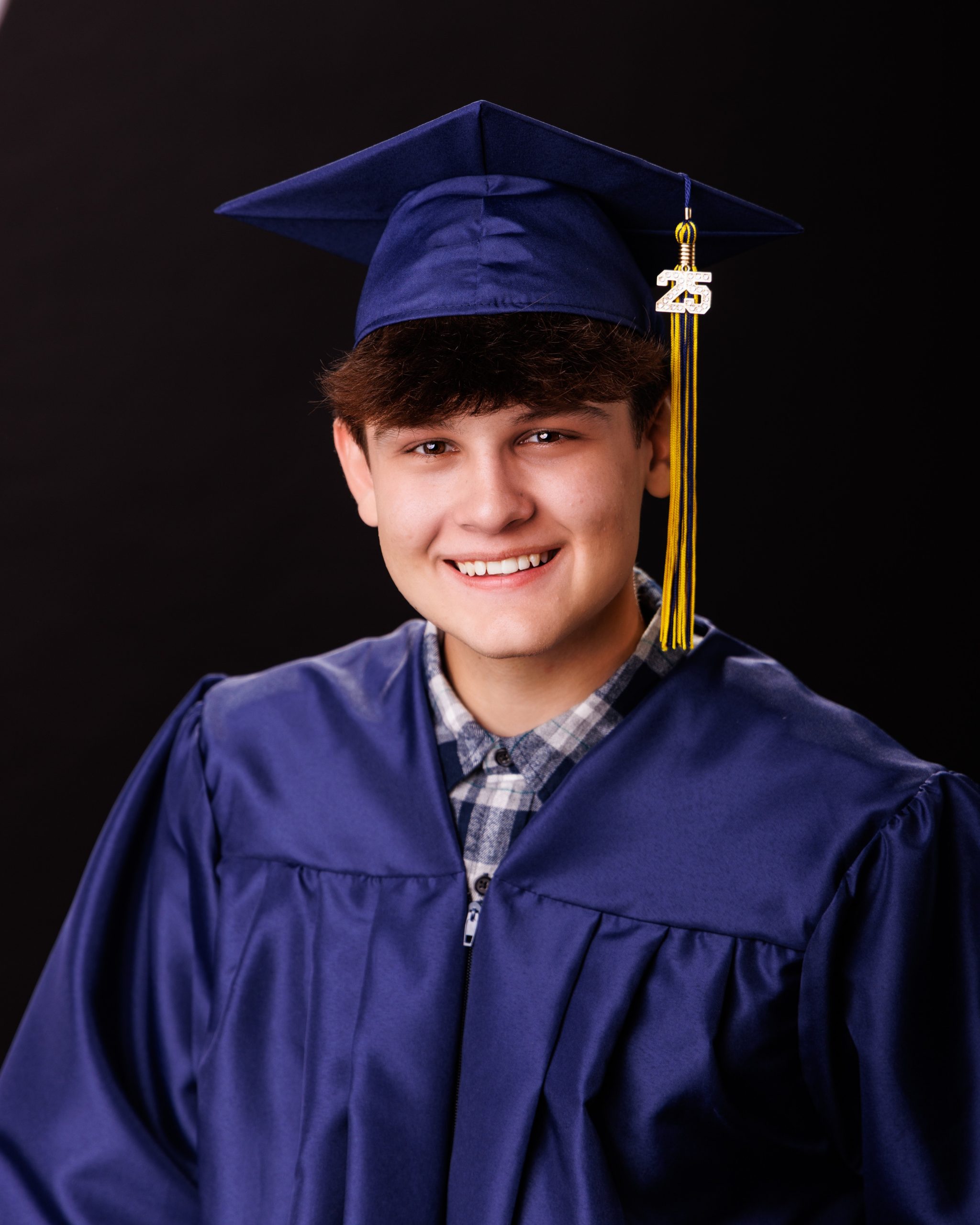 Close-up headshot of Andrew wearing graduation cap and gown