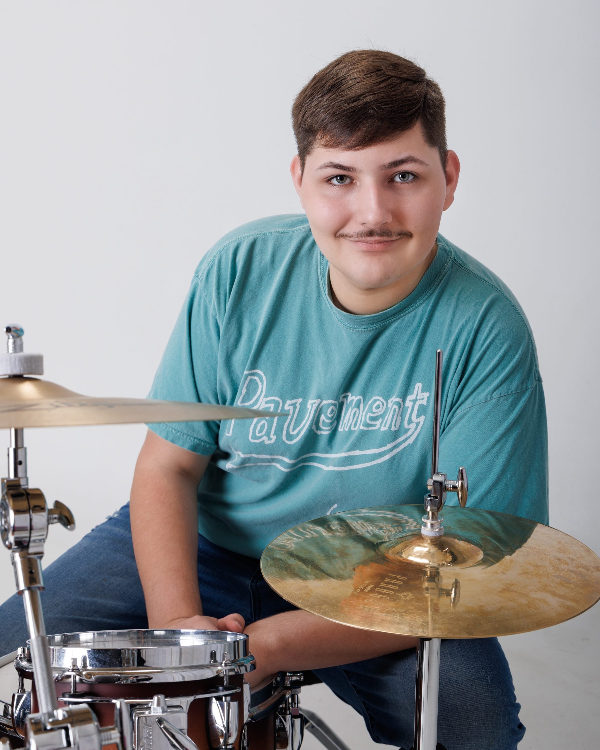 Tobias playing drums in casual teal shirt during Dearborn senior photography session at Studio ONE Wyandotte