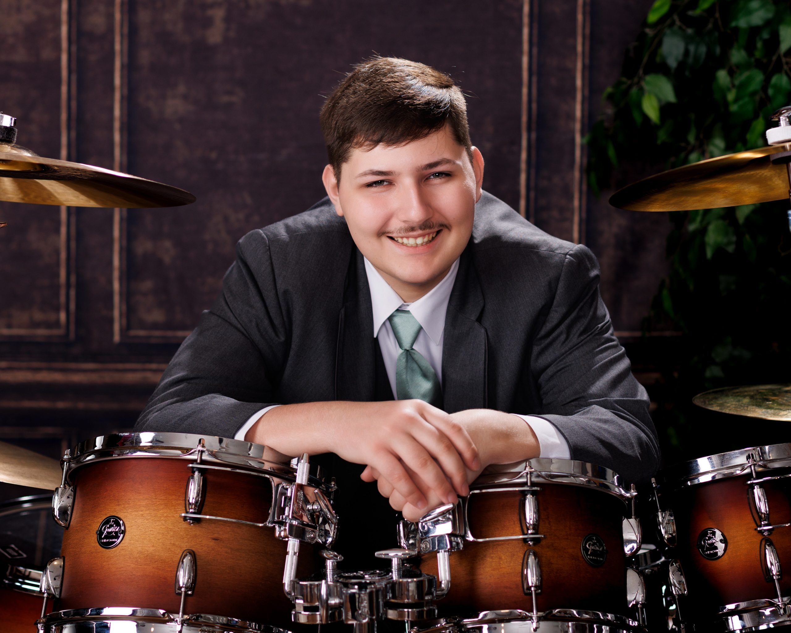Tobias standing confidently behind a full drum kit in formal attire