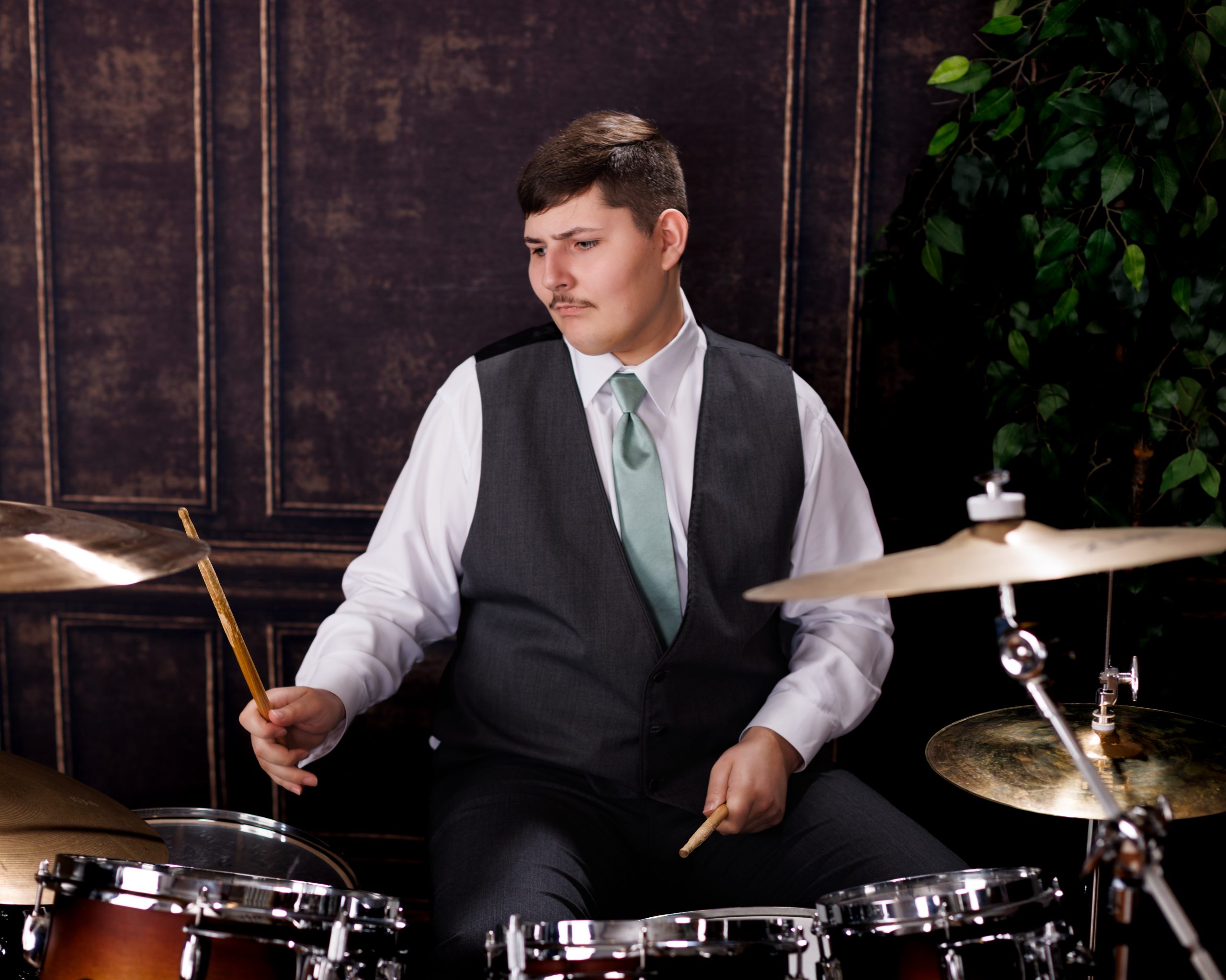 Tobias standing confidently behind a full drum kit in formal attire