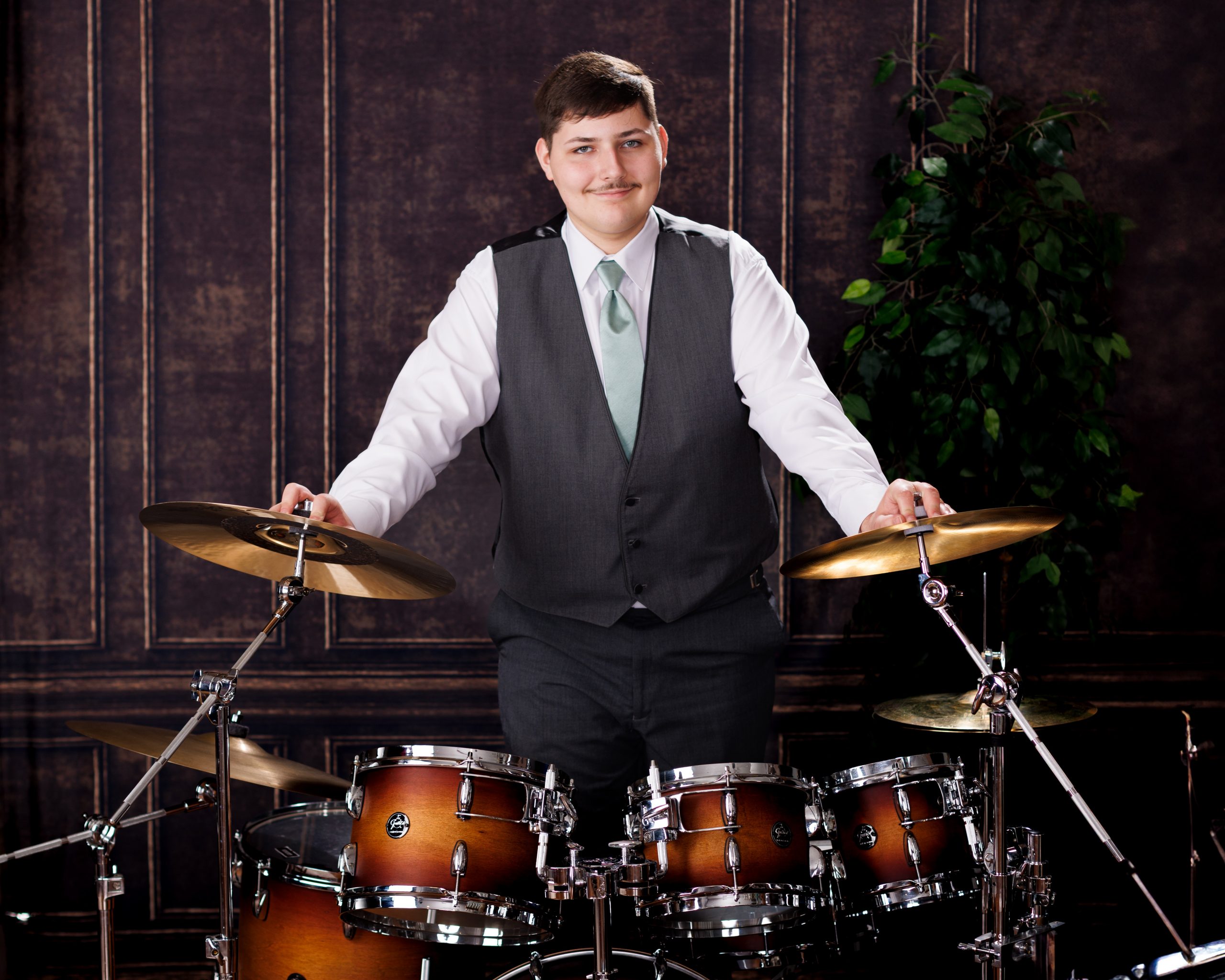 Tobias standing confidently behind a full drum kit in formal attire