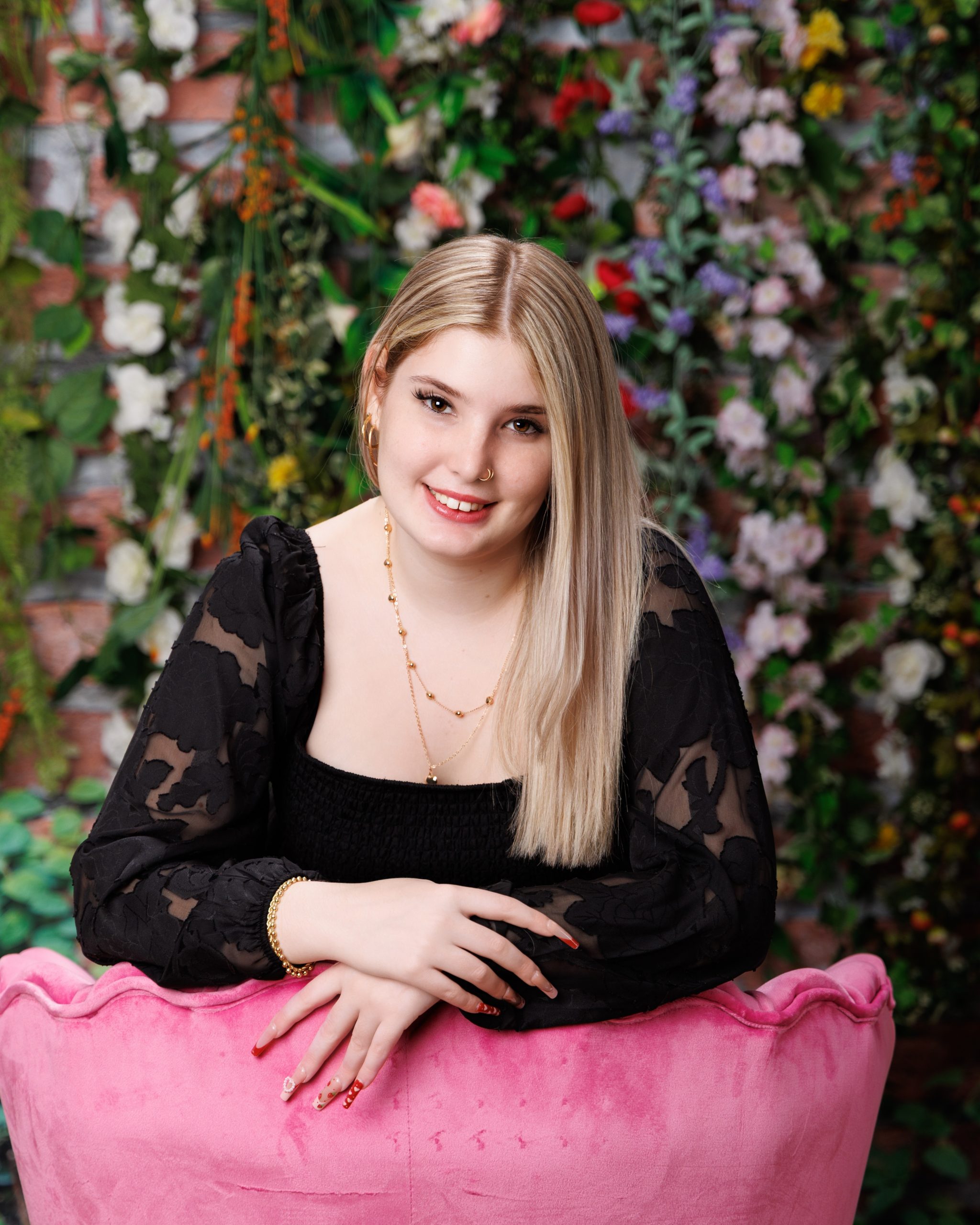 Alysha surrounded by pink peonies and yellow tulips in a sparkling curtain setting