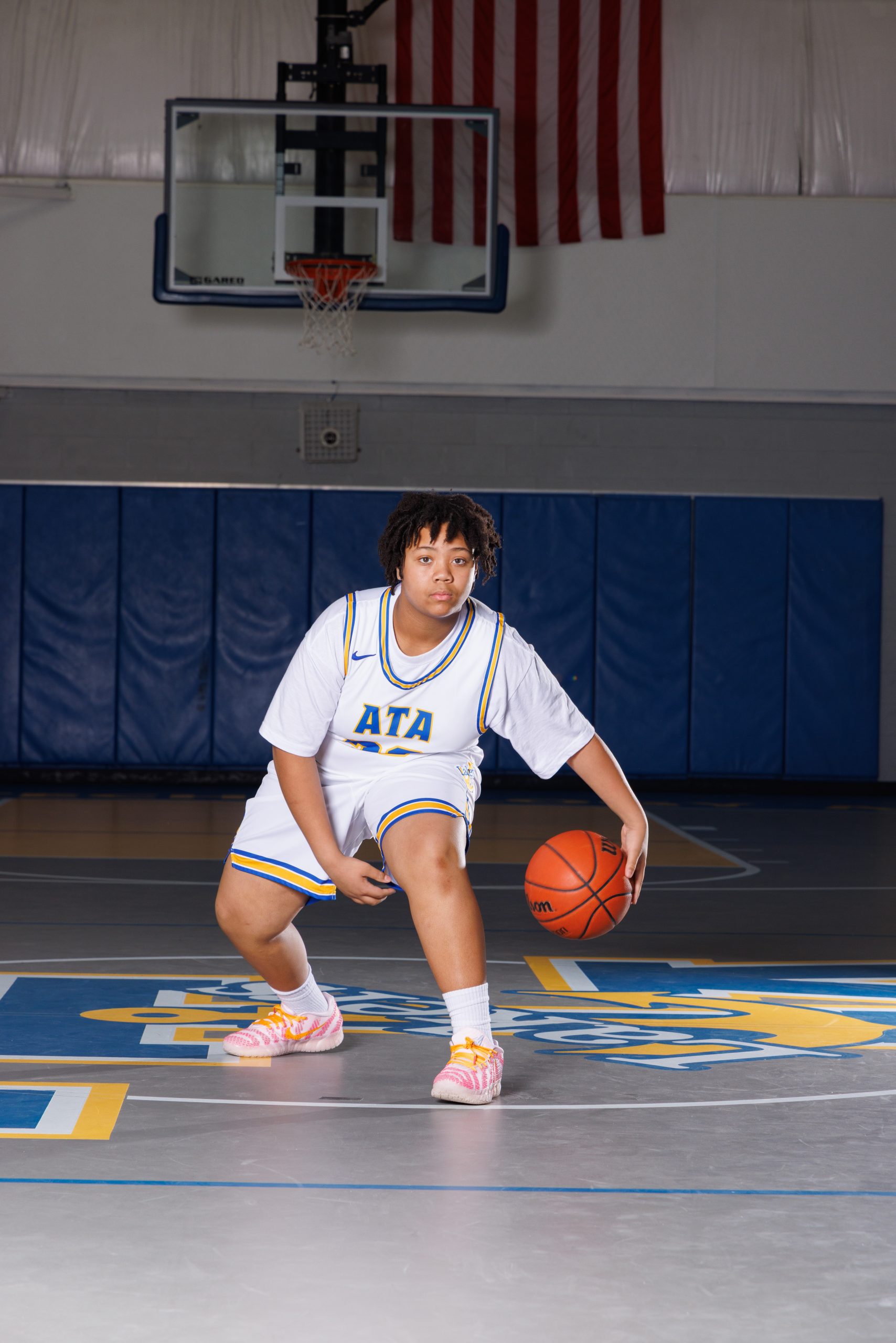High school basketball player holding ball in black Lakers uniform during a Wyandotte photography session
