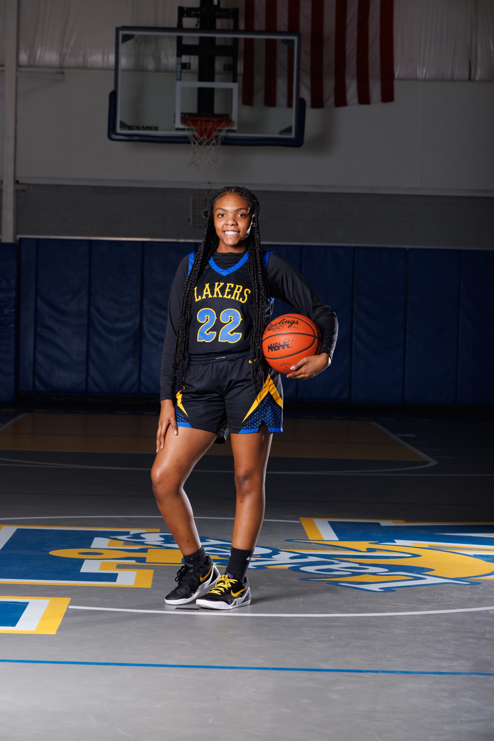 Cheerleader standing on basketball with pom-poms, showcasing team spirit in Detroit high school sports portraits