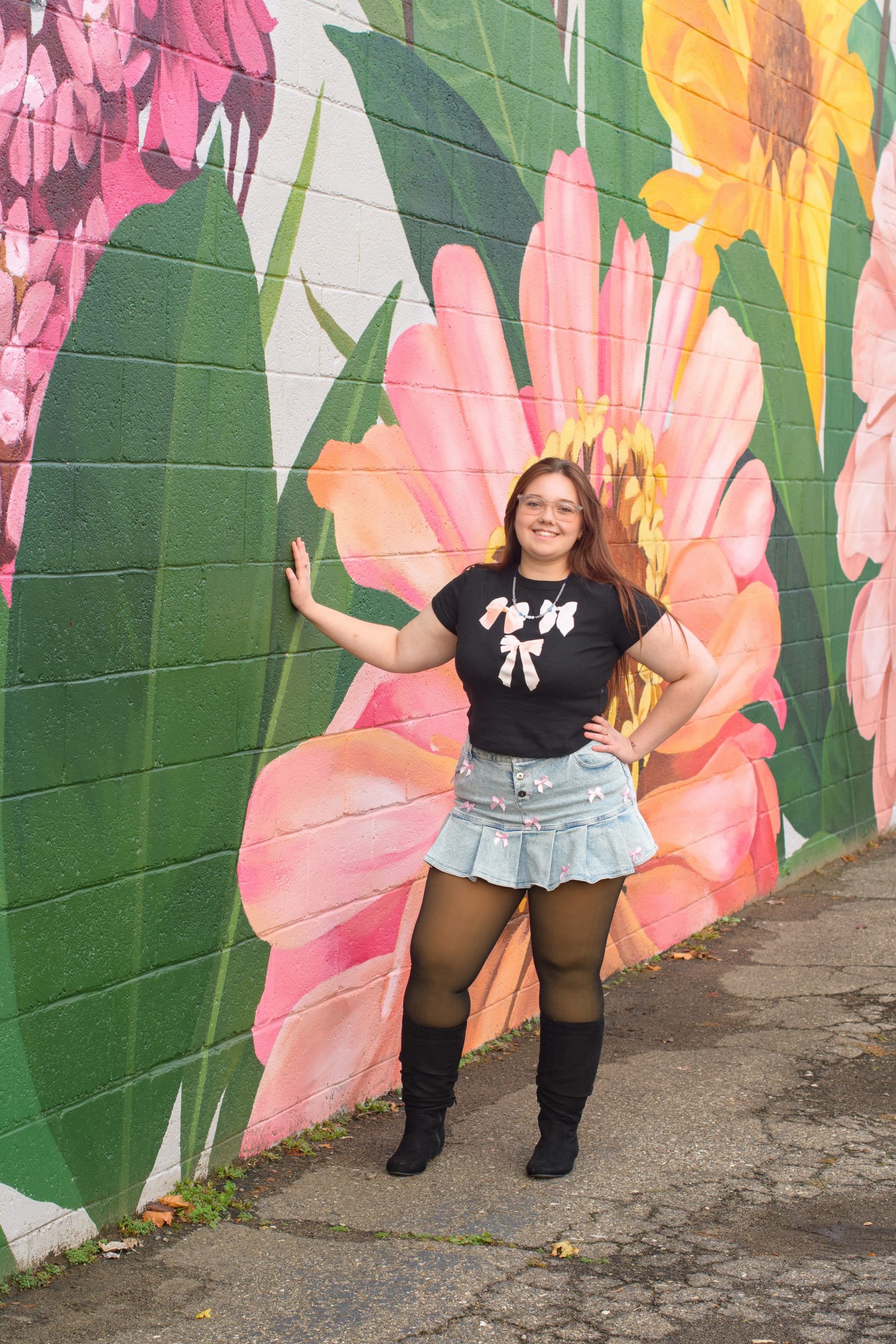 High school student smiling in red dress against a blue cityscape backdrop for Downriver senior photography