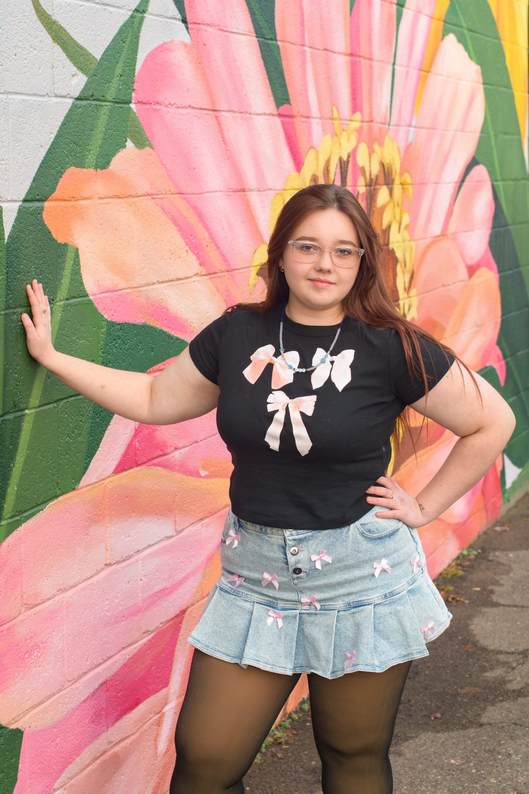 High school student smiling in red dress against a blue cityscape backdrop for Downriver senior photography
