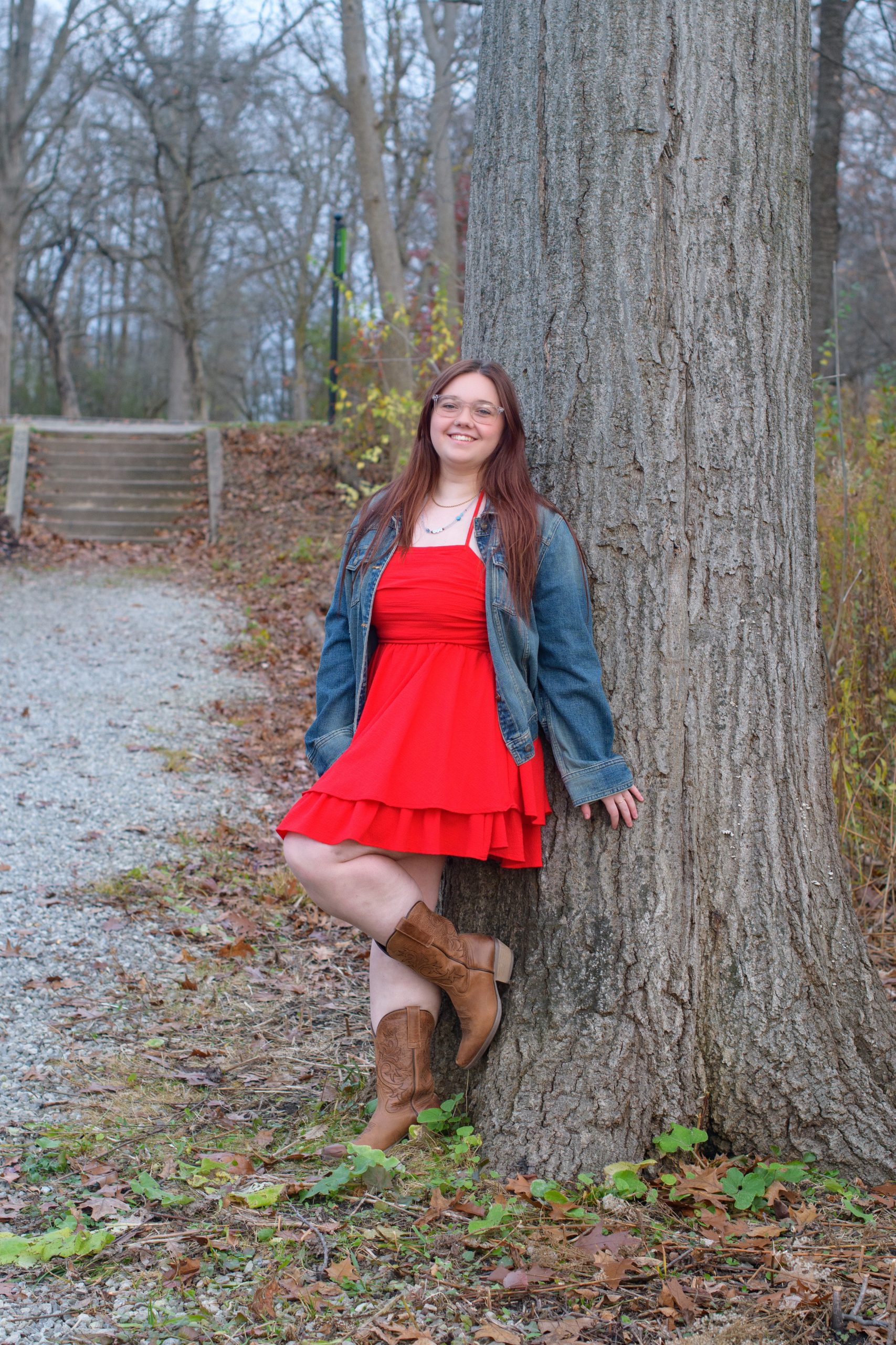 High school student smiling in red dress against a blue cityscape backdrop for Downriver senior photography