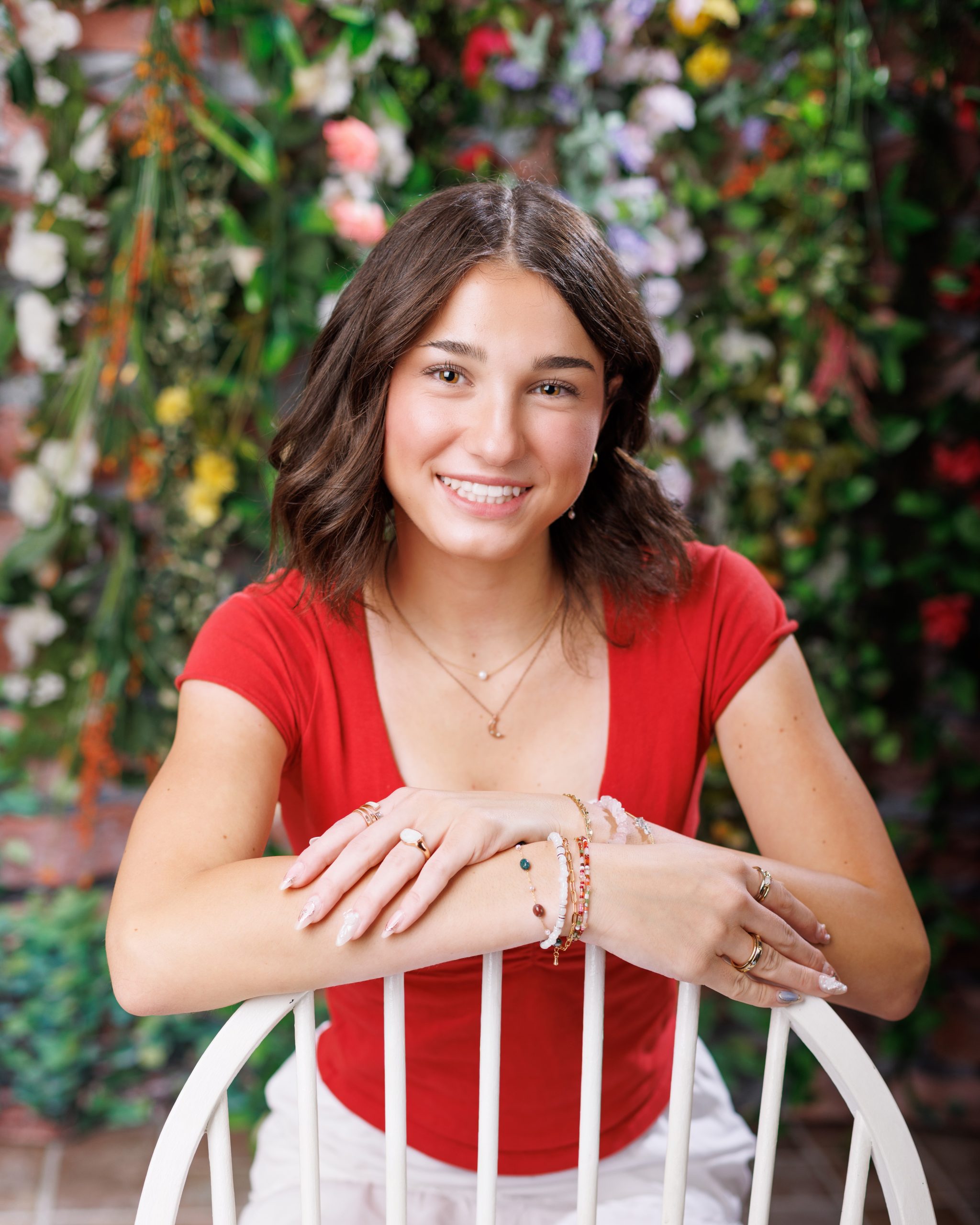 Anna poses with arms crossed against a rustic white door background for senior photography session
