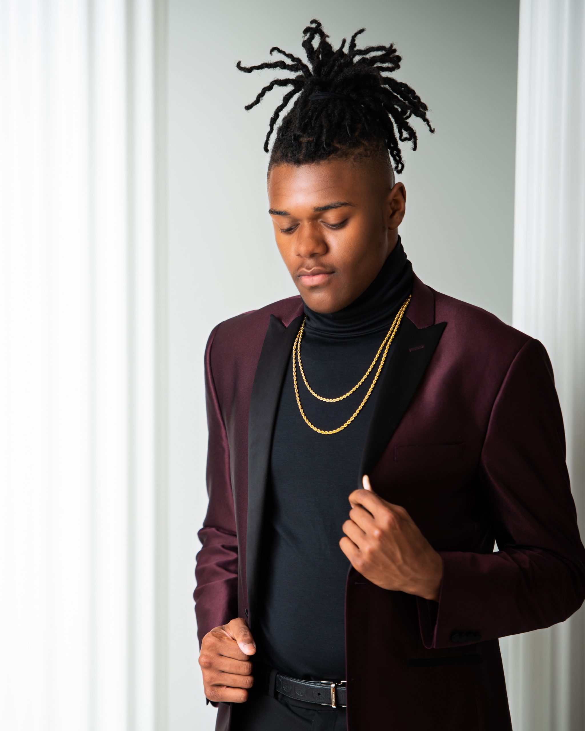 Frederick adjusting maroon suit jacket during studio senior photography session