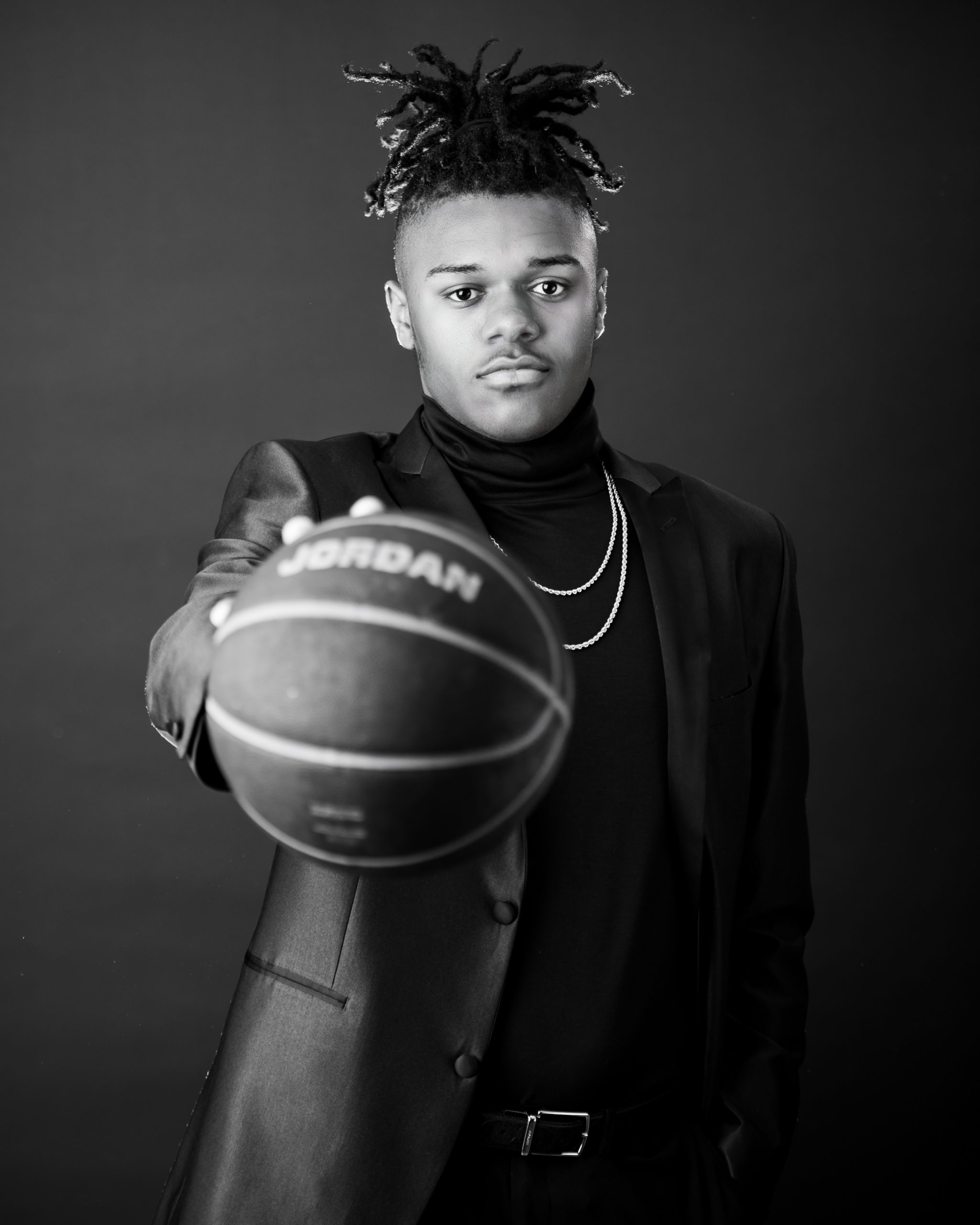Frederick wearing graduation cap and sneakers on graffiti wall in studio session