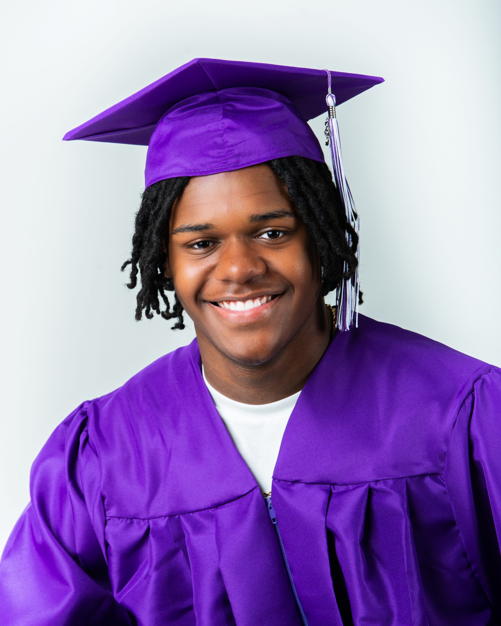Frederick wearing graduation cap and sneakers on graffiti wall in studio session