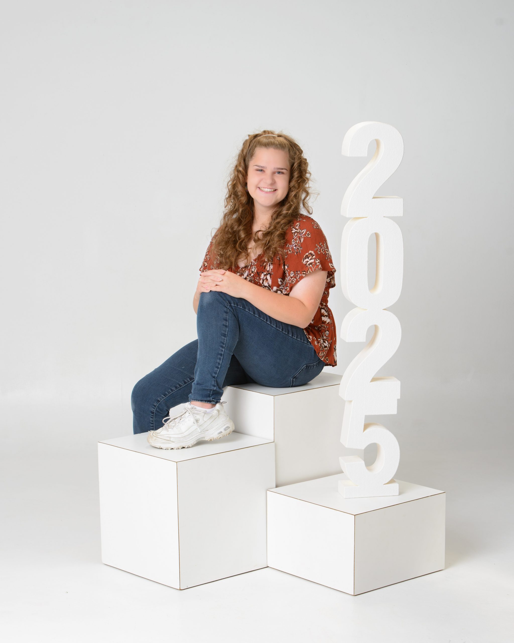 Lauren in white graduation gown and cap holding swing ropes for Downriver senior session