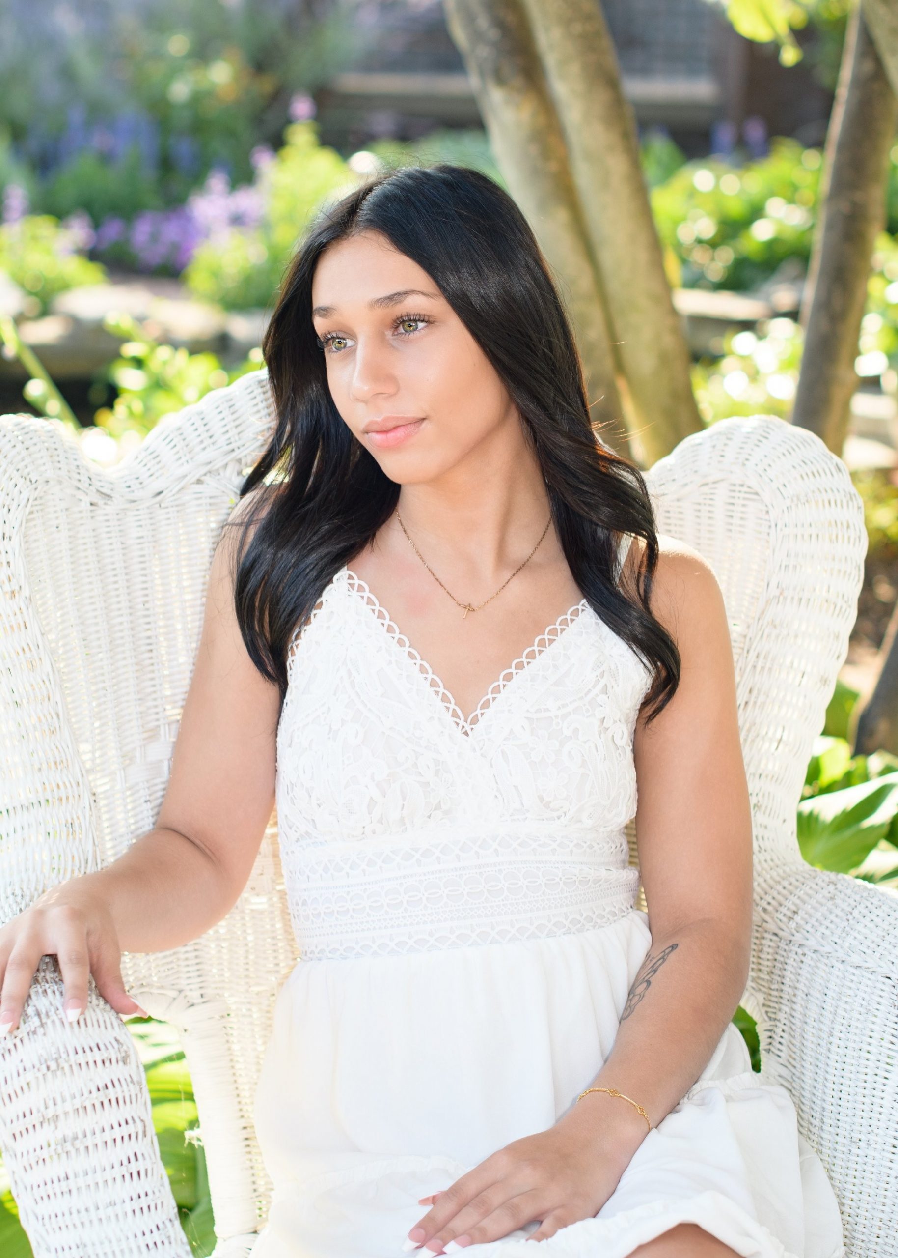 Outdoor senior portrait of a girl wearing a denim jacket over a white dress, surrounded by water lilies at Jordan Park