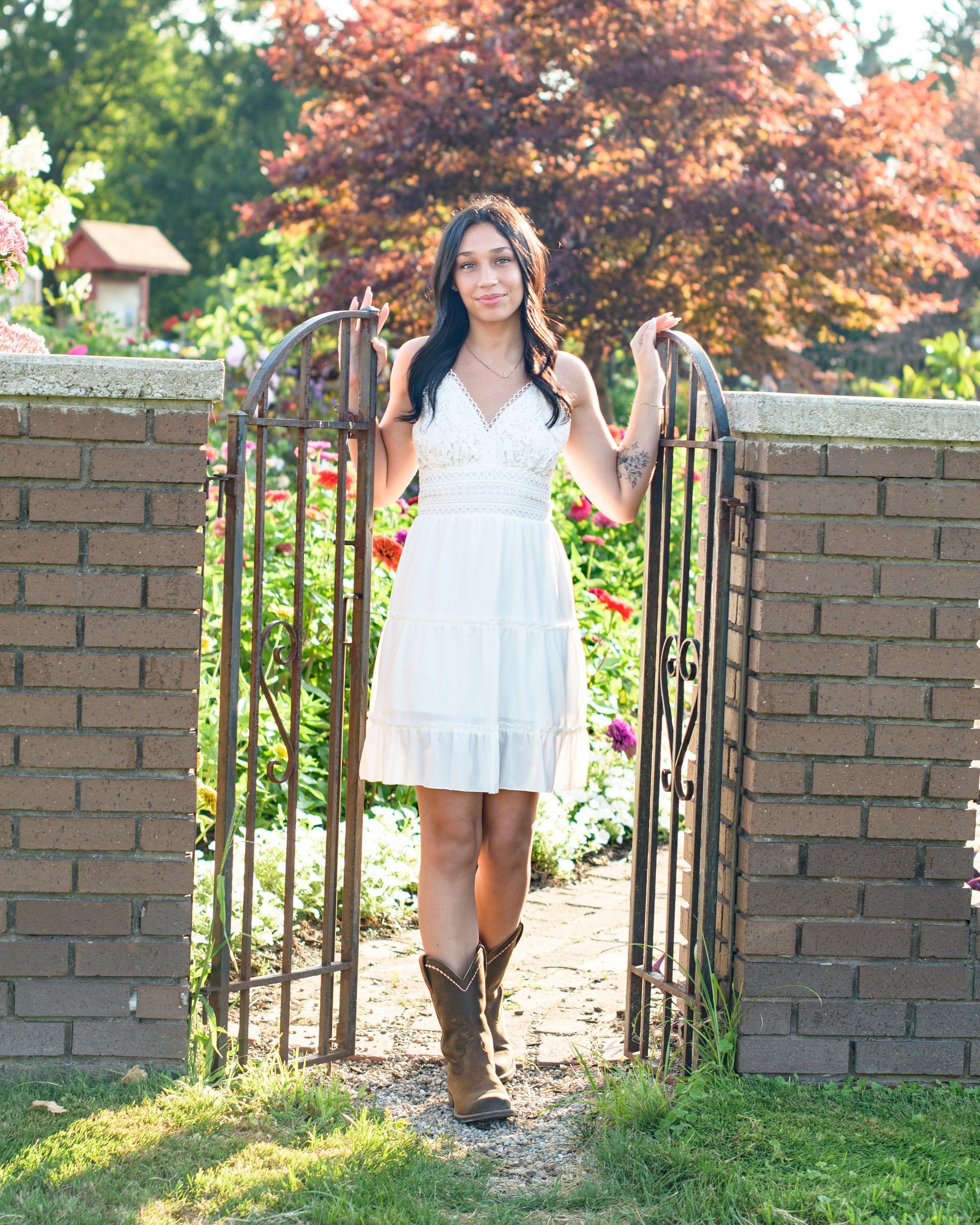 Natural light senior photography in a park setting, showcasing a young woman's casual style with a visible butterfly tattoo