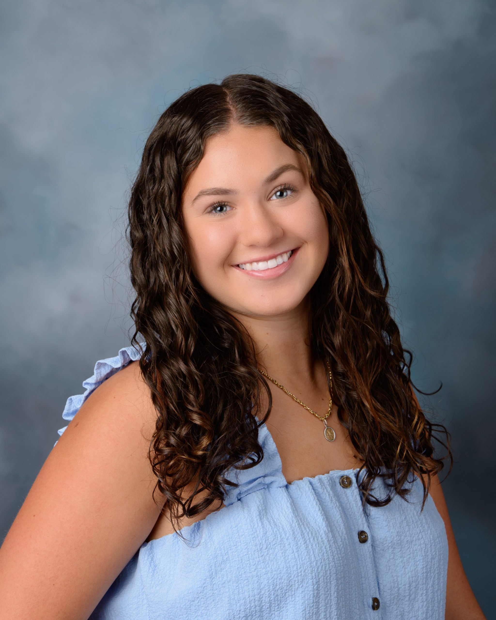 Senior headshot featuring braided hairstyle, black off-shoulder top, pearl necklace, and Downriver photography studio background