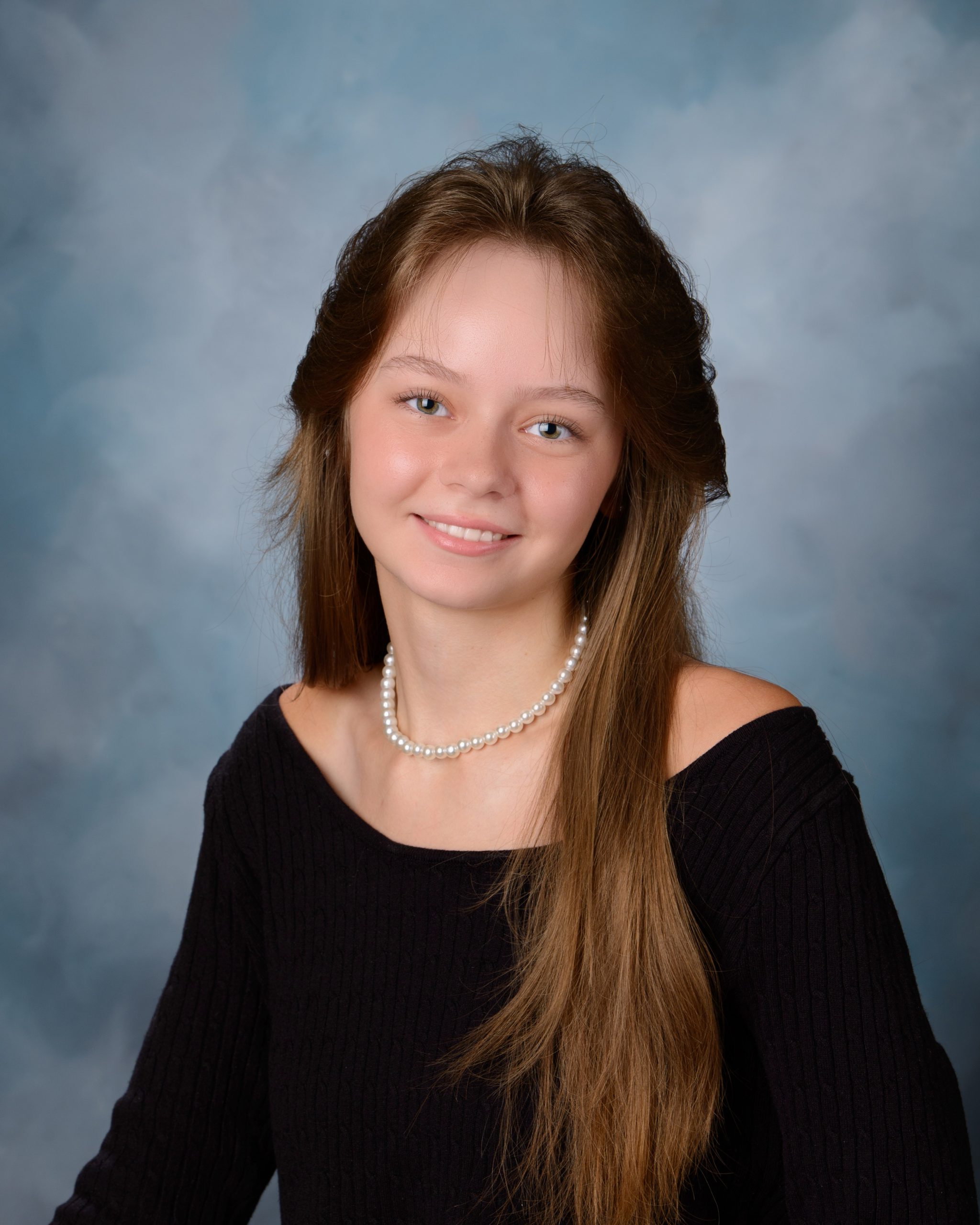 Senior headshot featuring braided hairstyle, black off-shoulder top, pearl necklace, and Downriver photography studio background