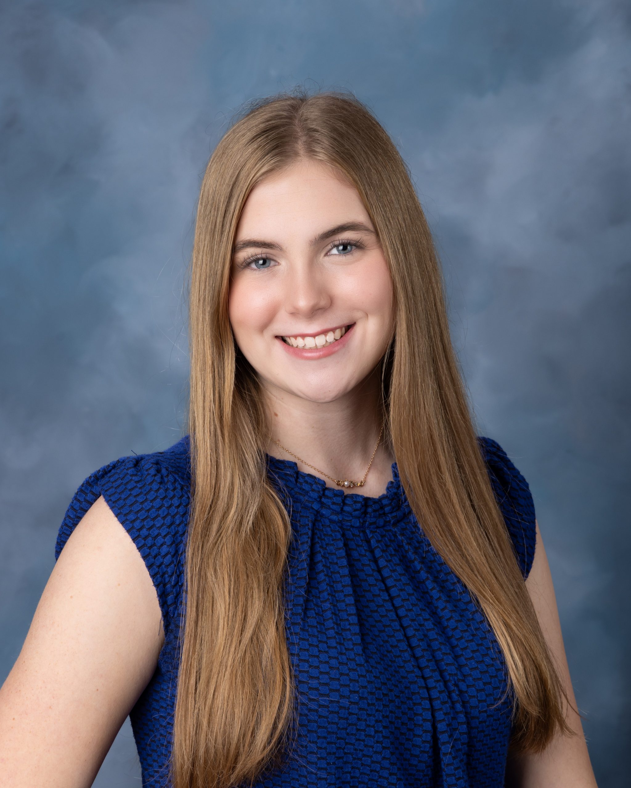 Senior headshot featuring braided hairstyle, black off-shoulder top, pearl necklace, and Downriver photography studio background
