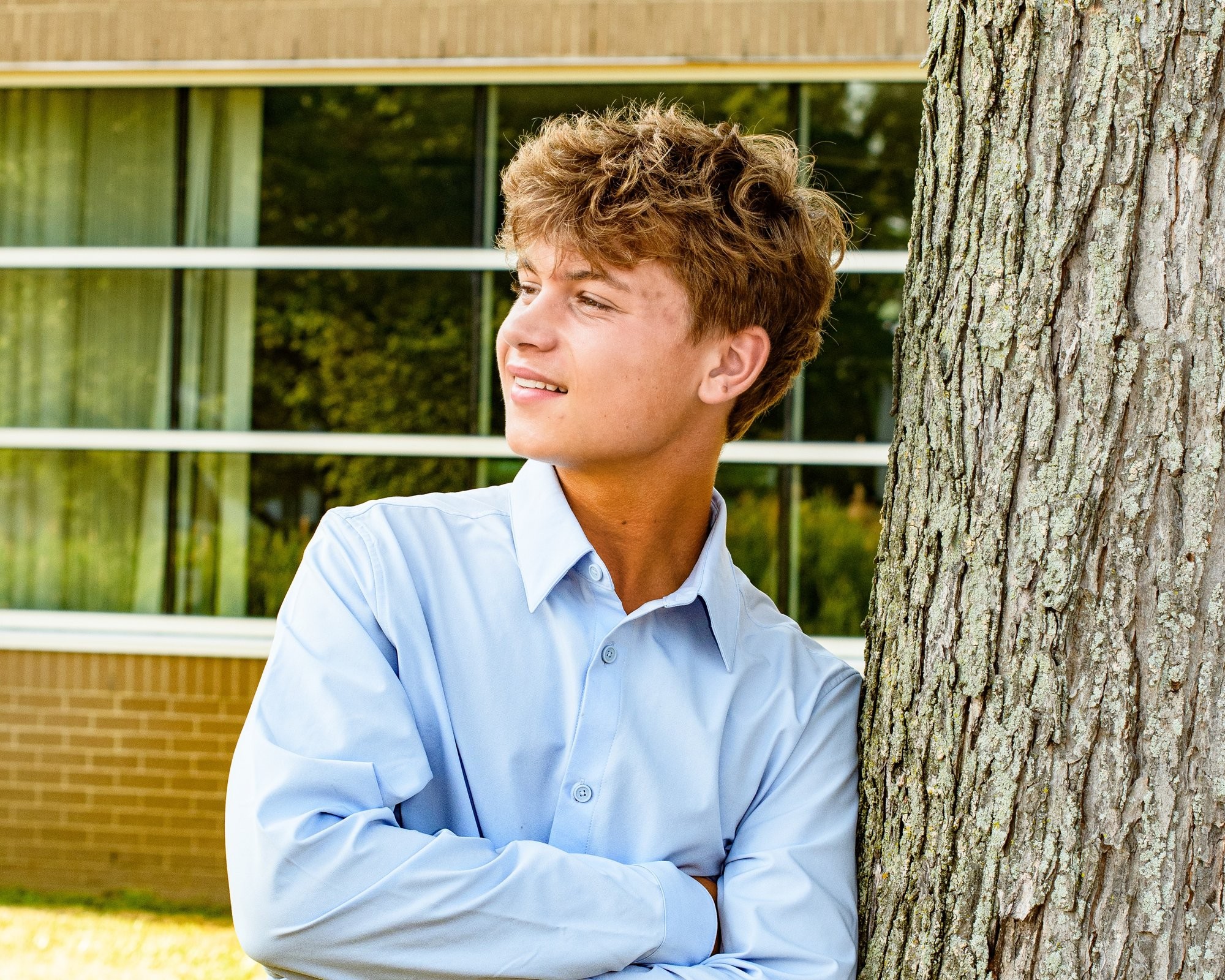Student portrait during Grosse Isle High School senior photo location session, wearing striped shirt and gray pants on grass