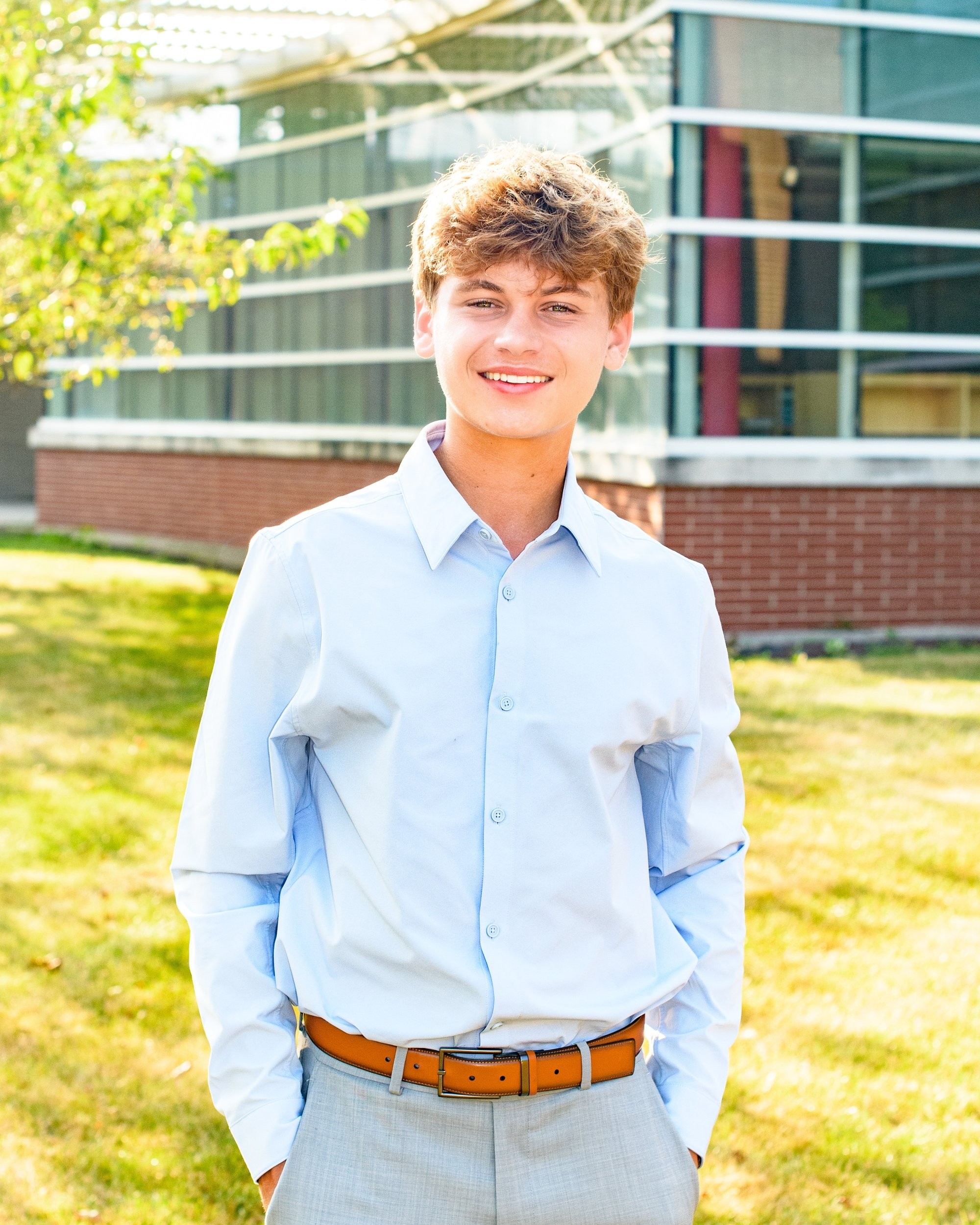 Student portrait during Grosse Isle High School senior photo location session, wearing striped shirt and gray pants on grass