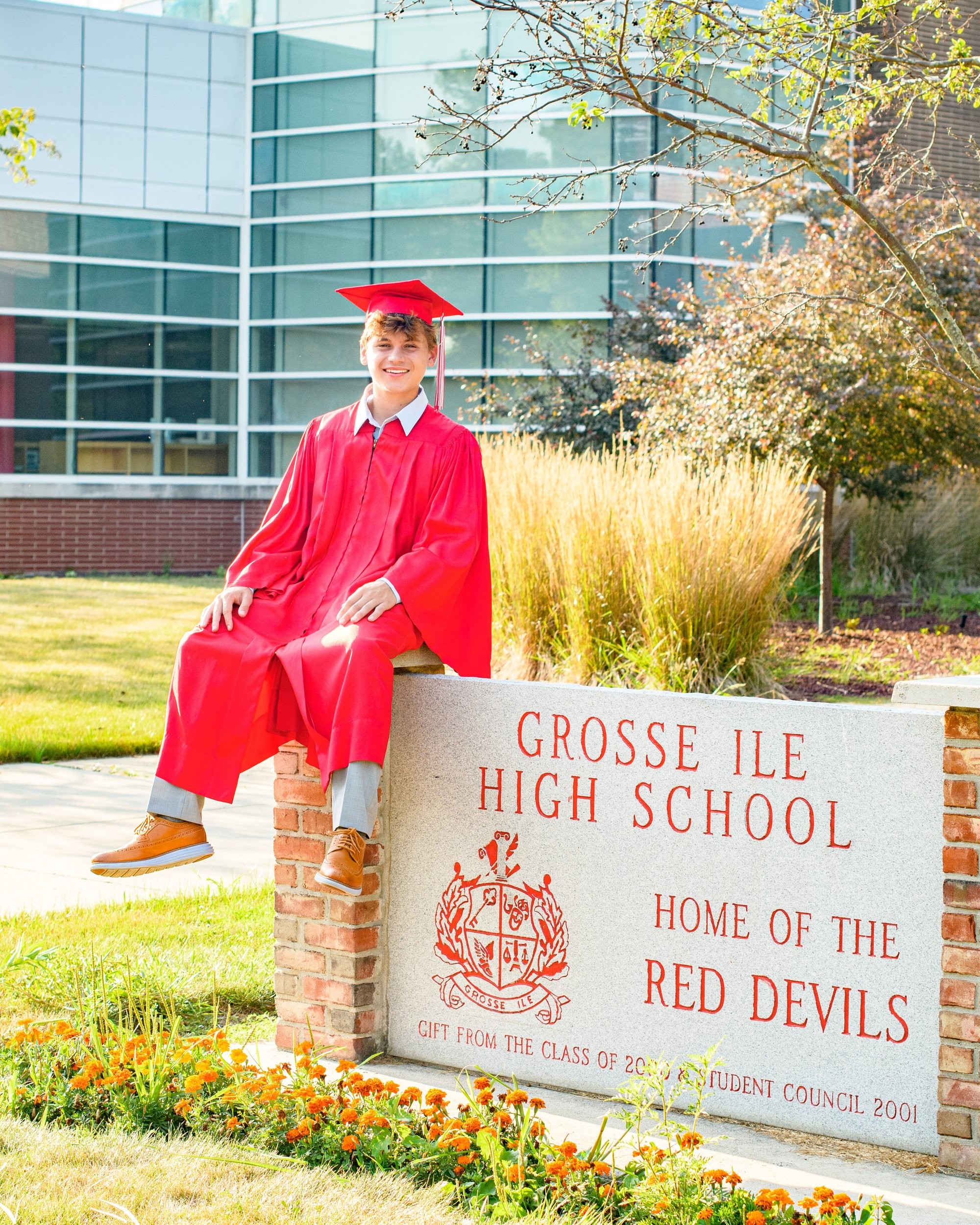 Student portrait during Grosse Isle High School senior photo location session, wearing striped shirt and gray pants on grass