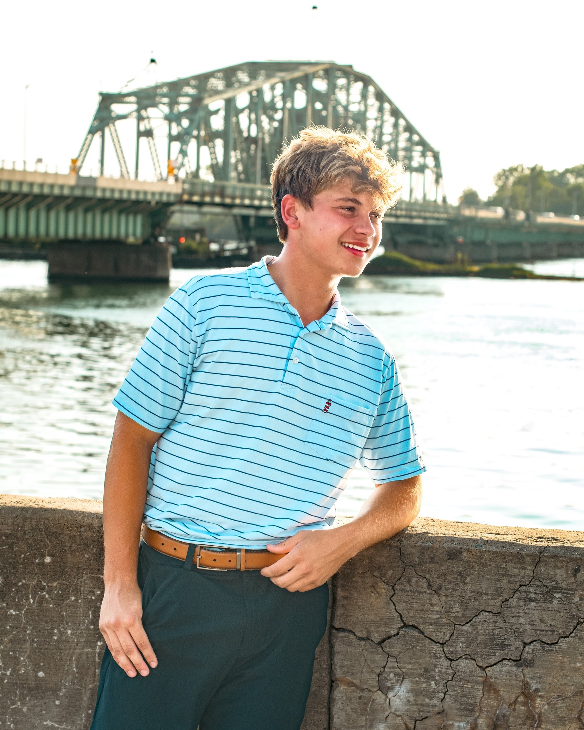 Student portrait during Grosse Isle High School senior photo location session, wearing striped shirt and gray pants on grass