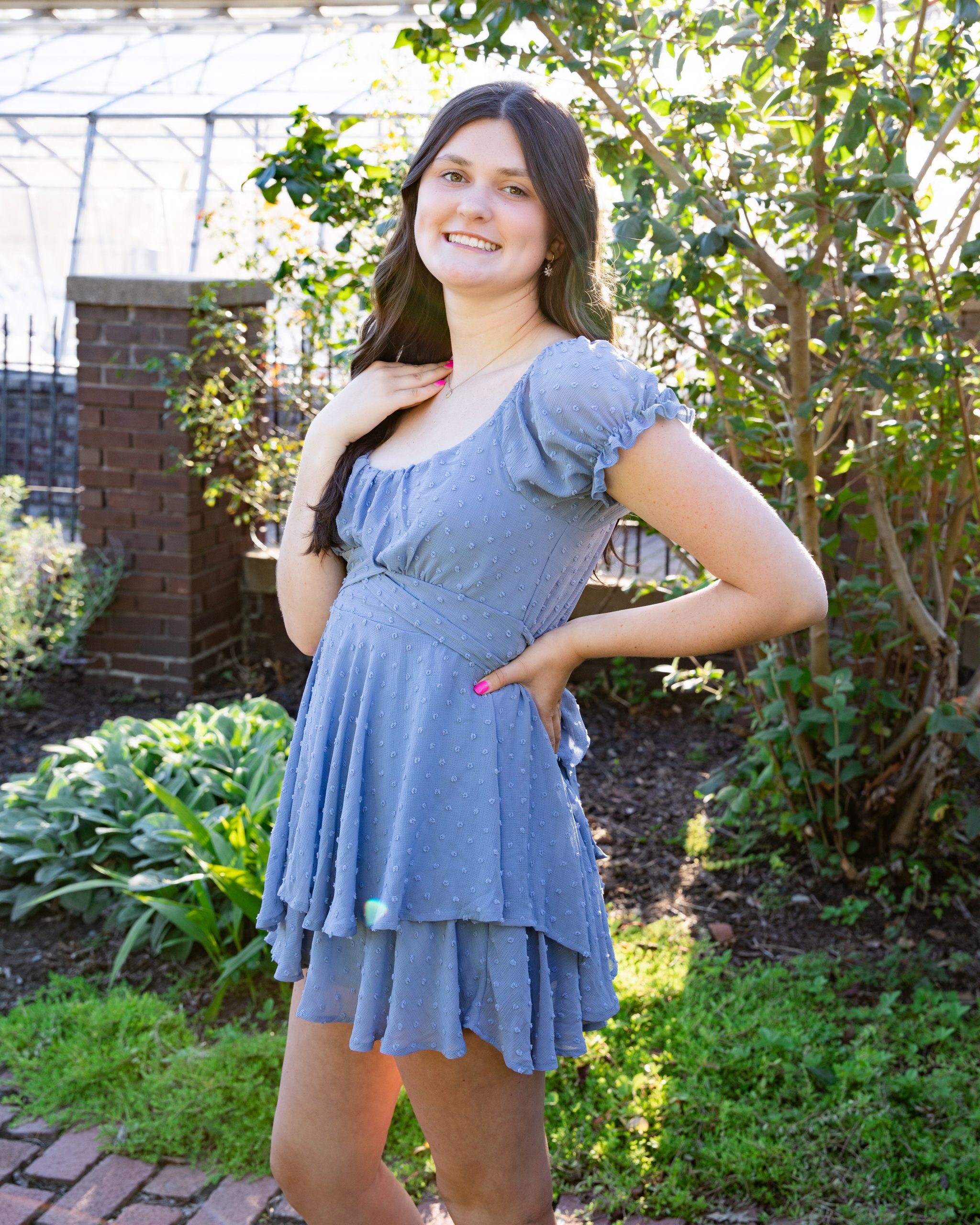 senior photography session featuring a young woman in blue dress and cowboy boots at Grosse Ile garden