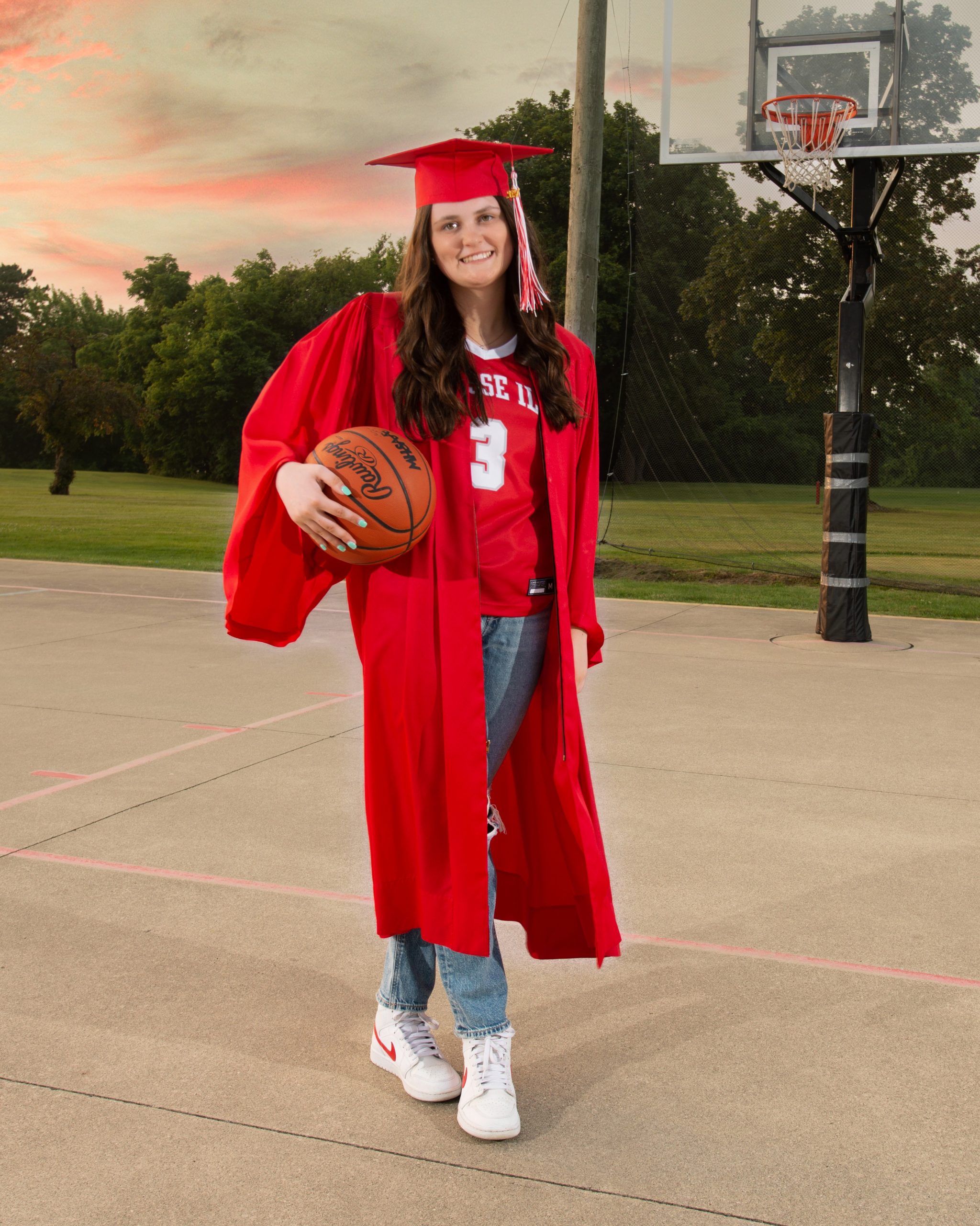 Grosse Ile student sitting on basketball court with ball, casual pose