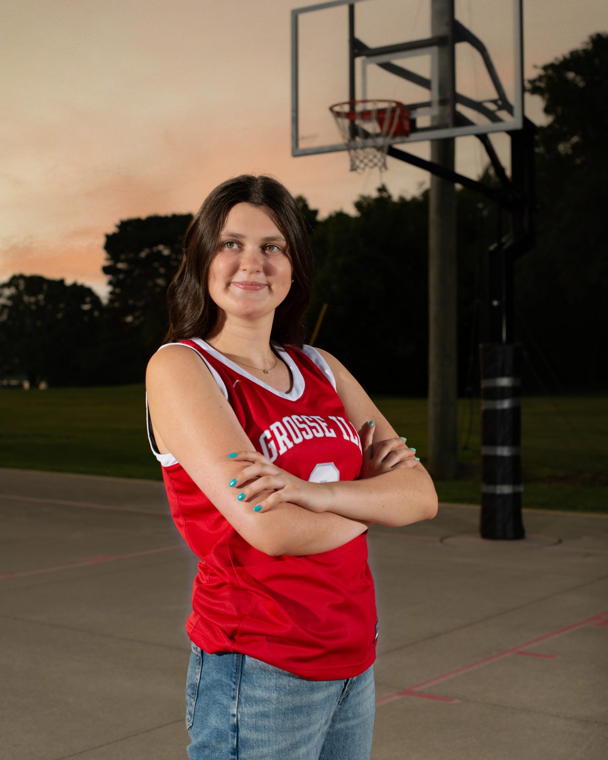 Grosse Ile student sitting on basketball court with ball, casual pose