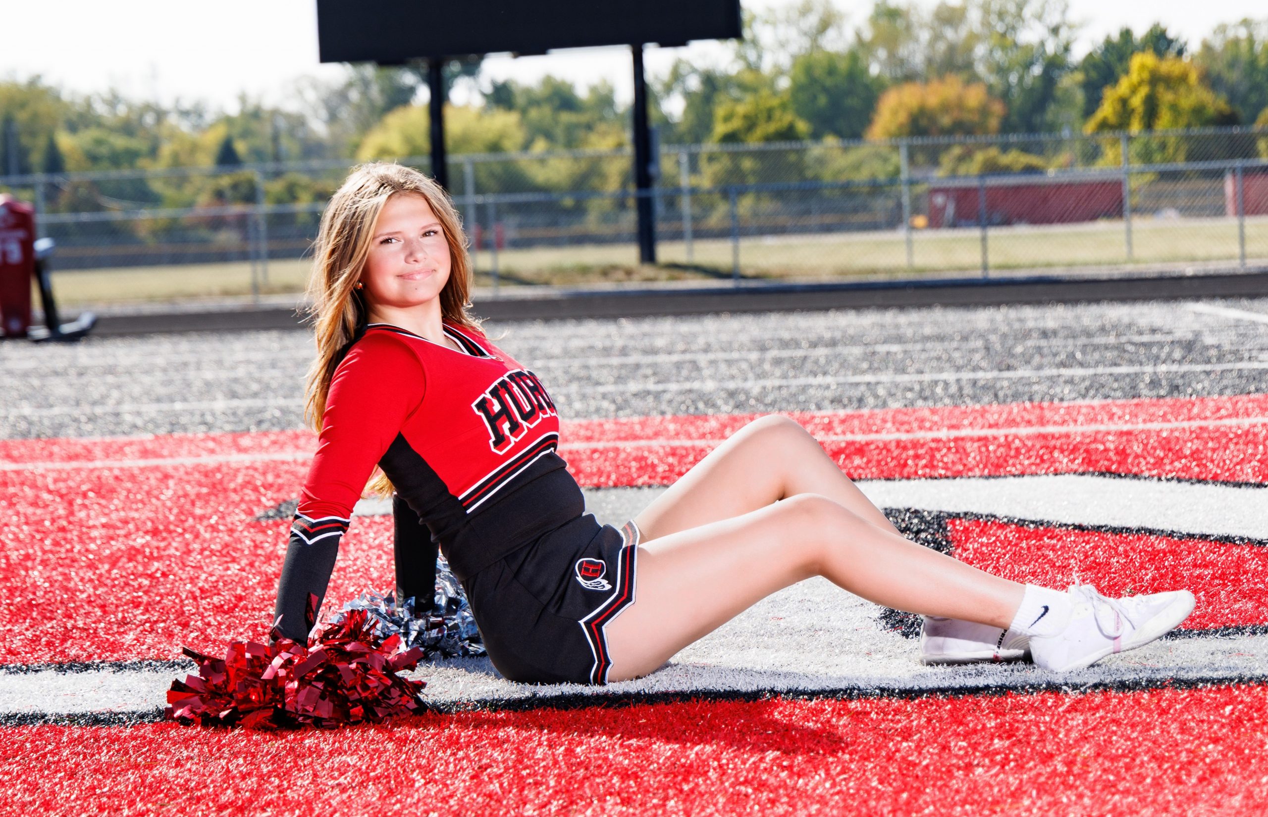 Huron cheer team photo featuring white pom-poms and athletic field backdrop