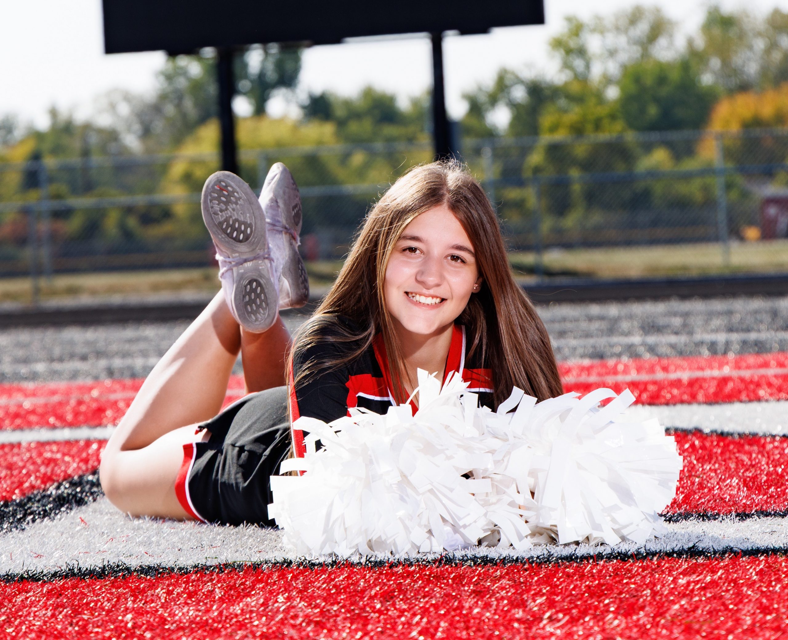 Huron cheer team photo featuring white pom-poms and athletic field backdrop