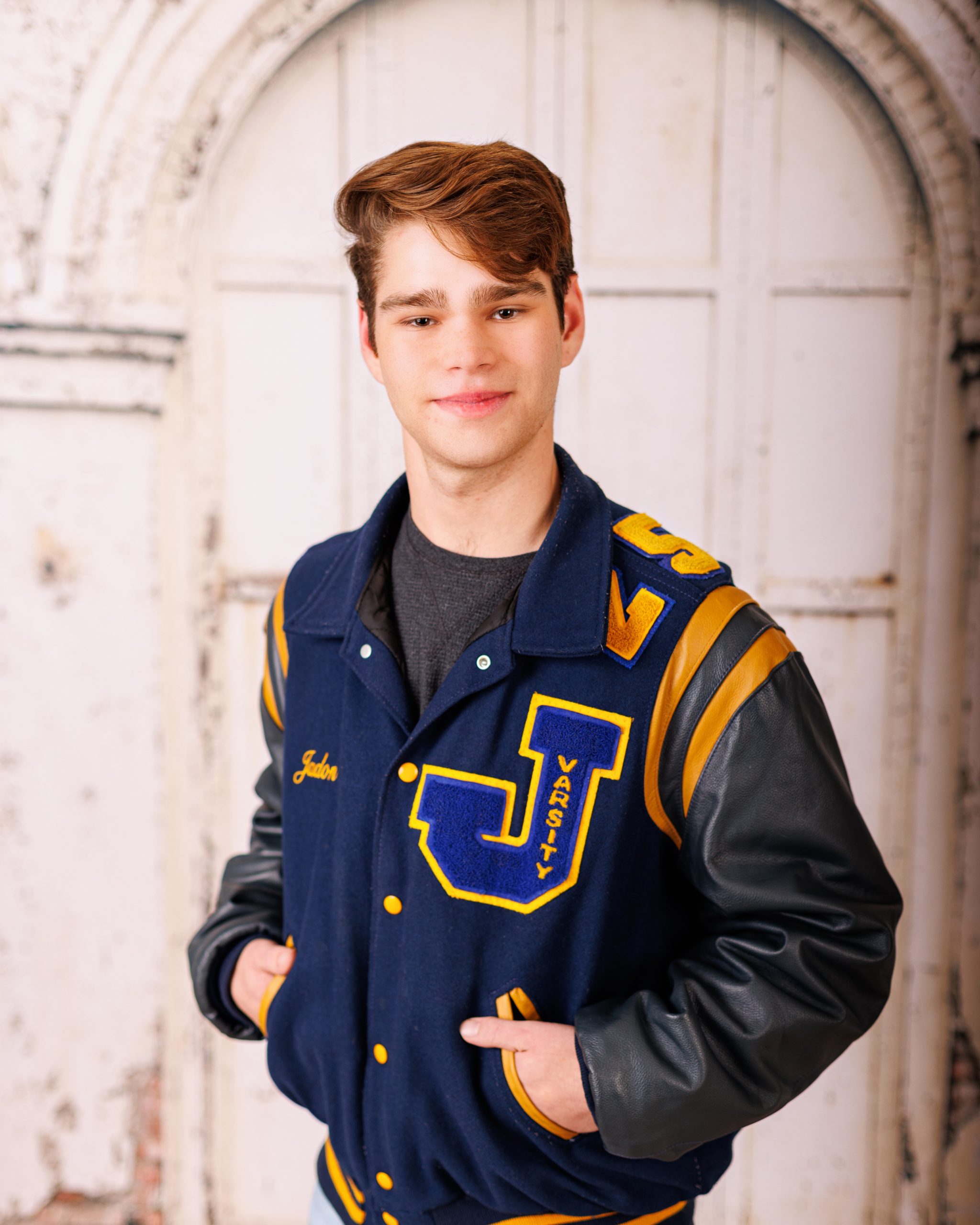 Senior portrait of Jefferson High School student wearing navy varsity jacket with 'J' emblem