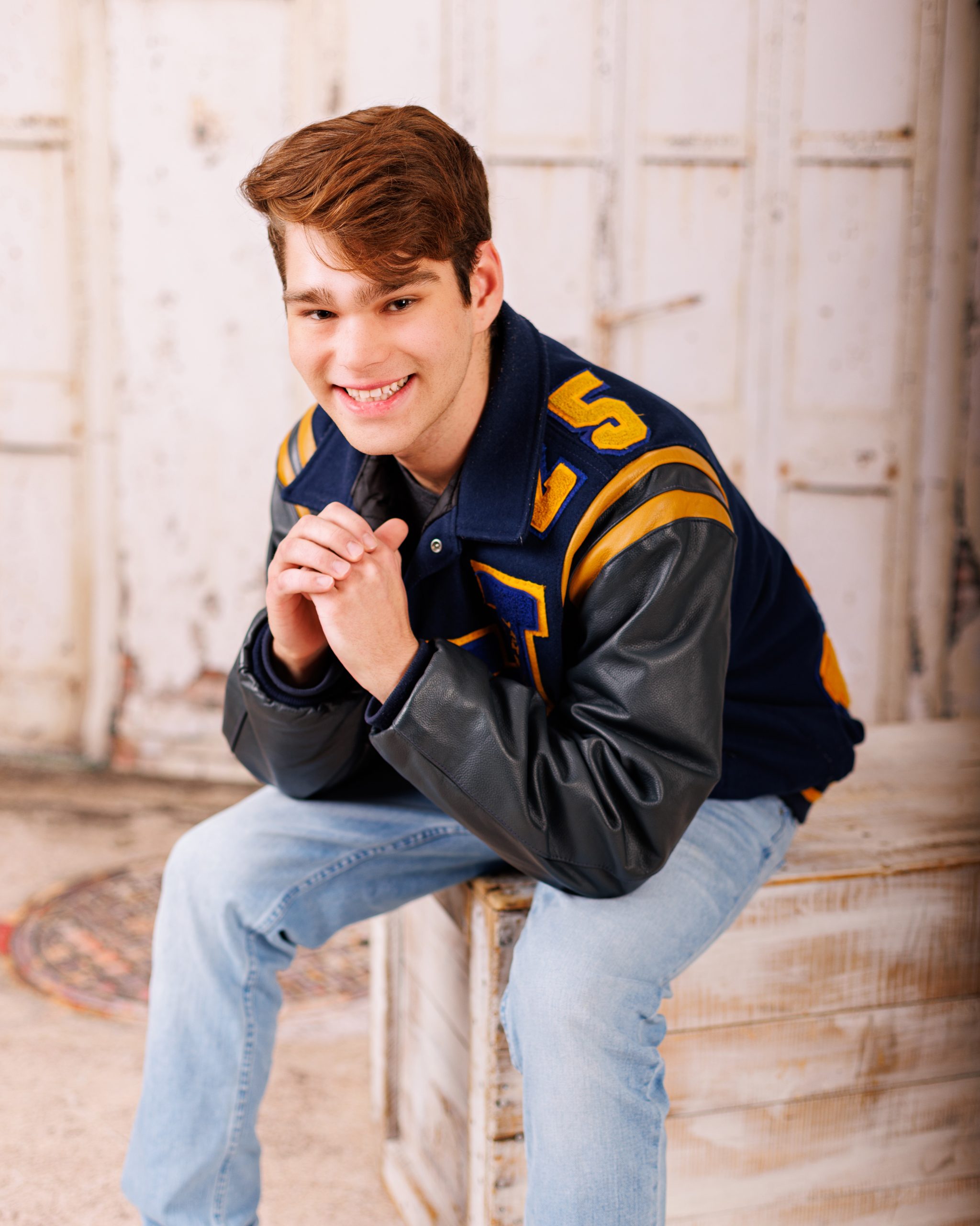 Stylishly dressed young man in a navy three-piece suit posing confidently against a dark backdrop.