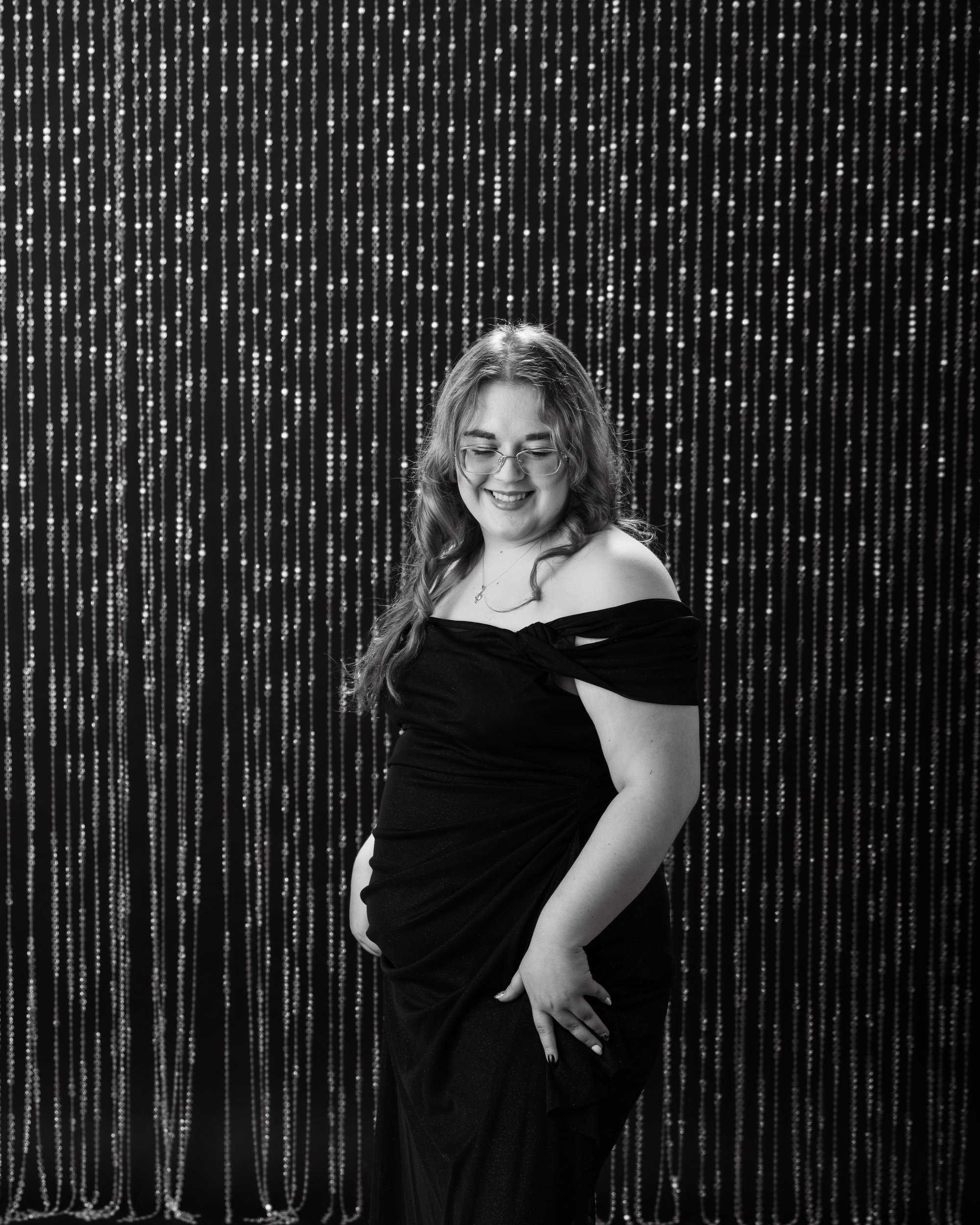 Kayla's black-and-white senior portrait against a beaded curtain background