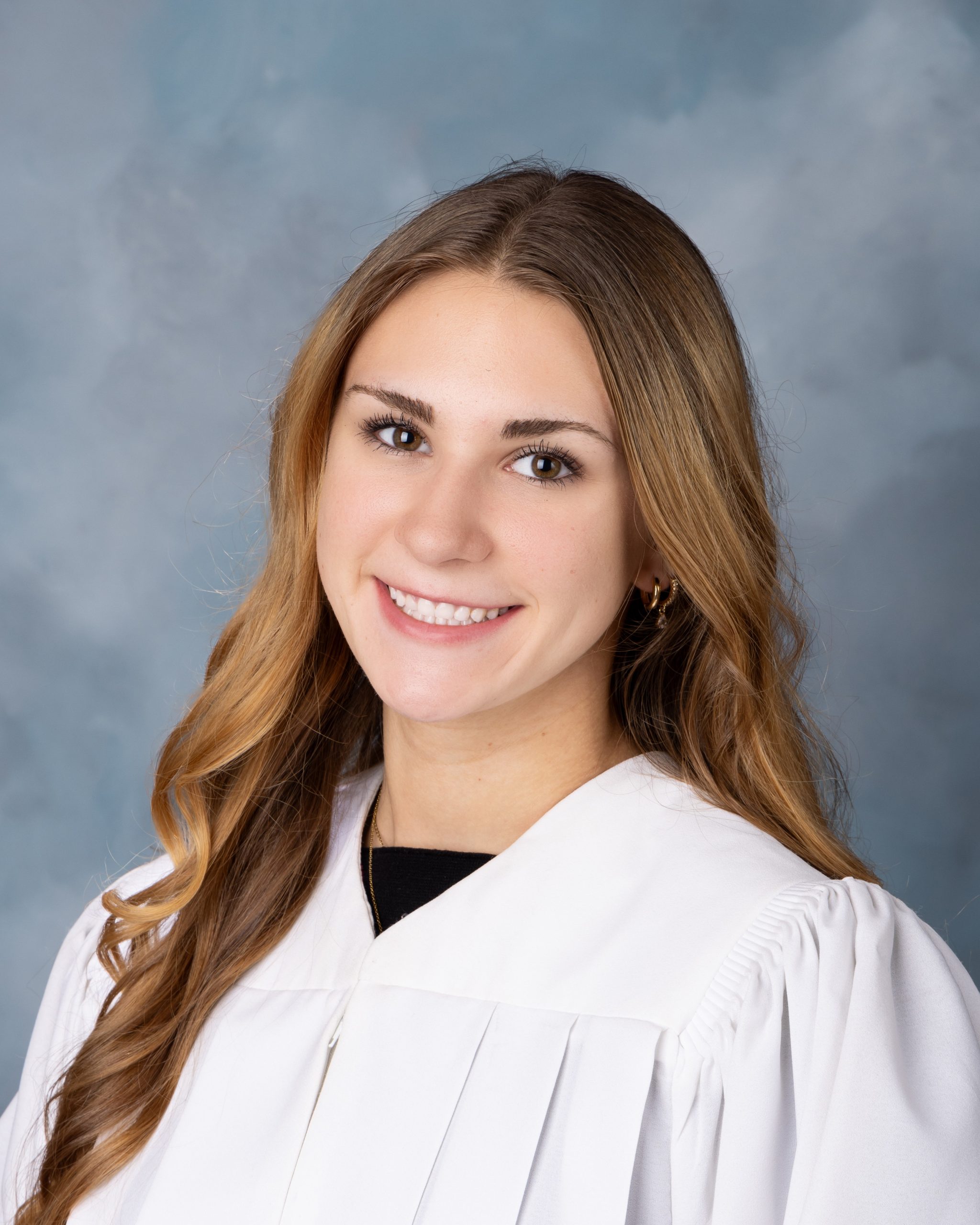 Madelyn's senior yearbook photo from Cabrini High School, featuring a smiling student with long hair and a black top against a blue studio background.
