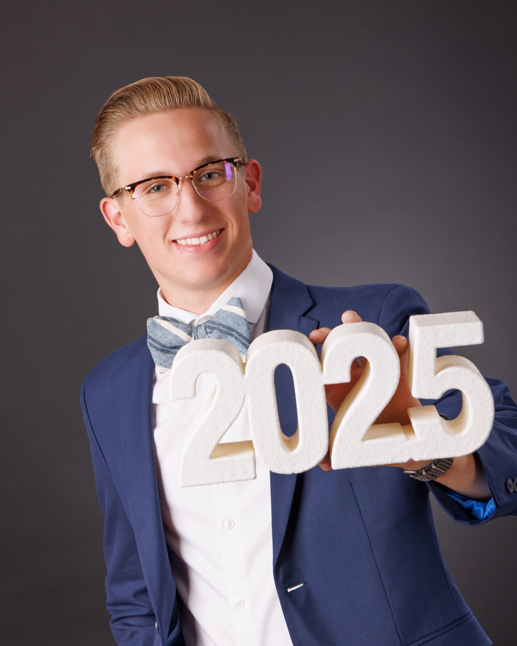Plymouth senior photo session student wearing graduation gown holding '2025' cutout