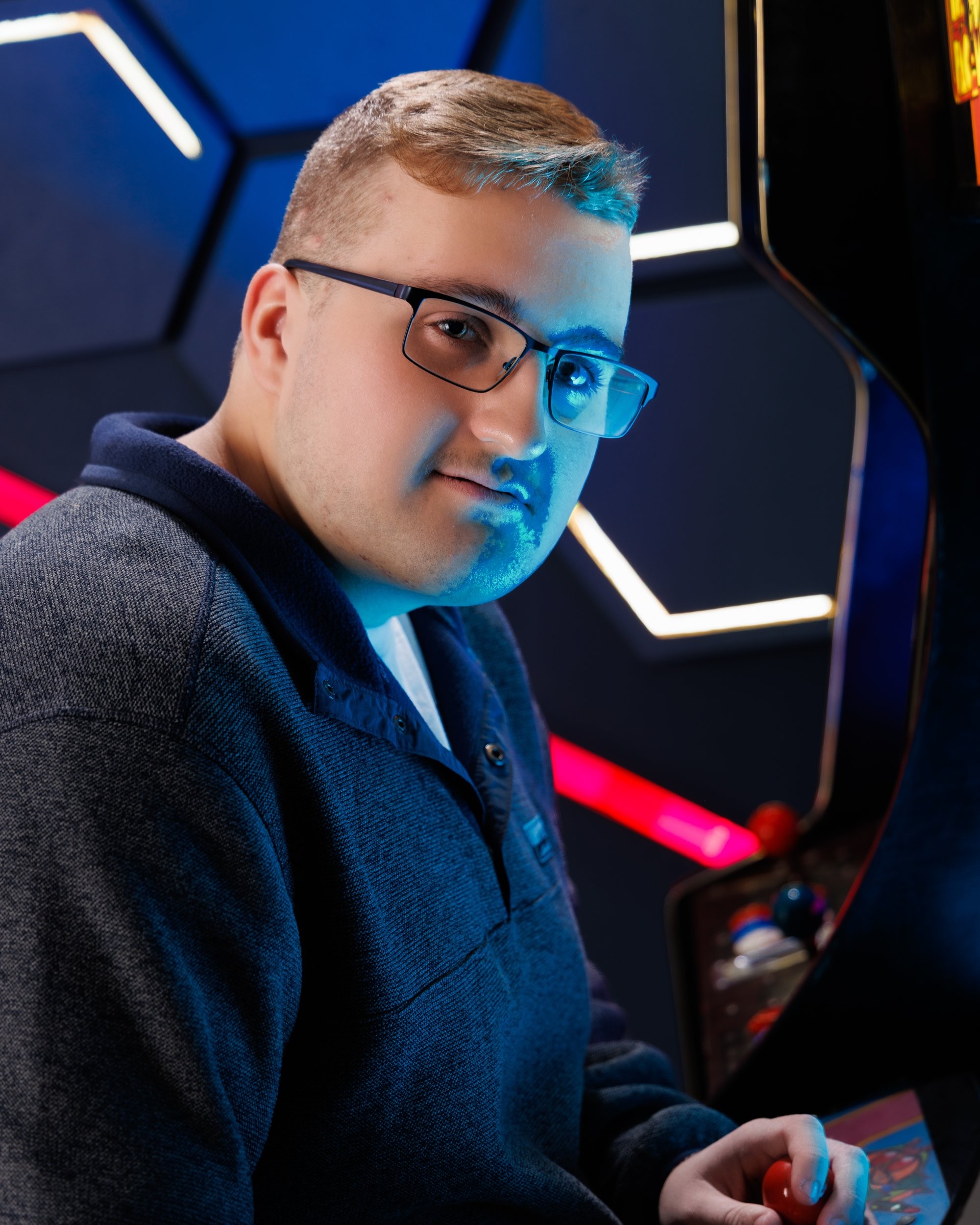 Black-and-white senior portrait of Aiden at an arcade machine, Downriver photography style