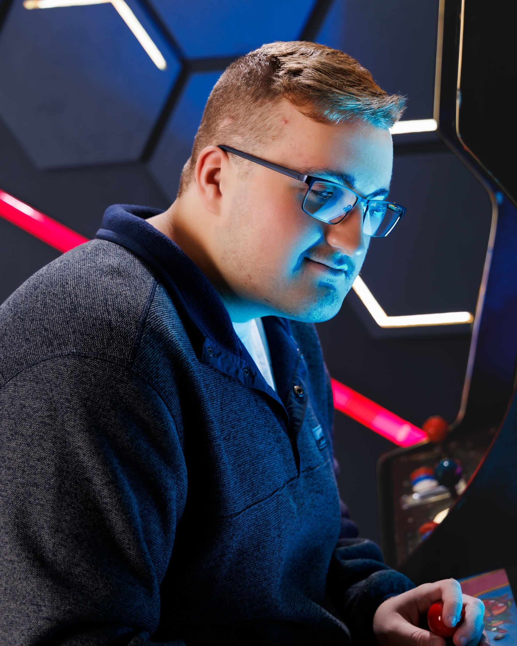 Aiden holding a 'Street Fighter' arcade cabinet in a colorful photo session