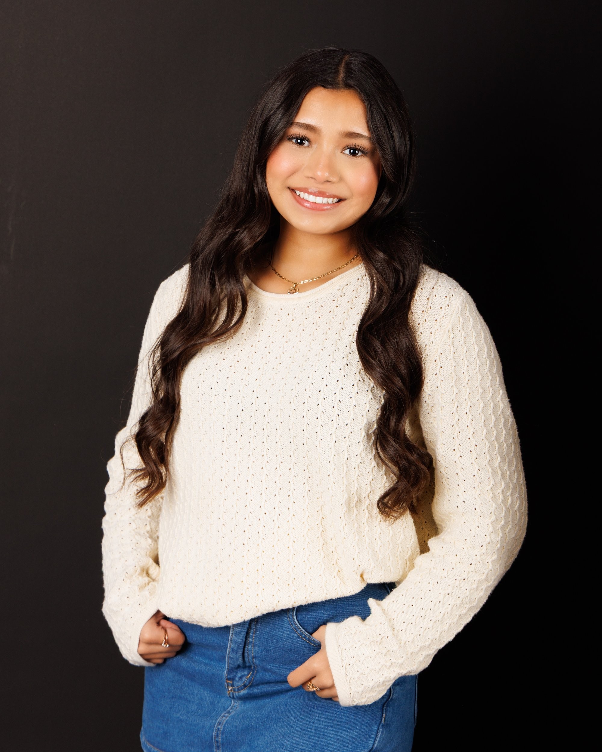 Maria in cream sweater with varsity jacket draped over shoulder