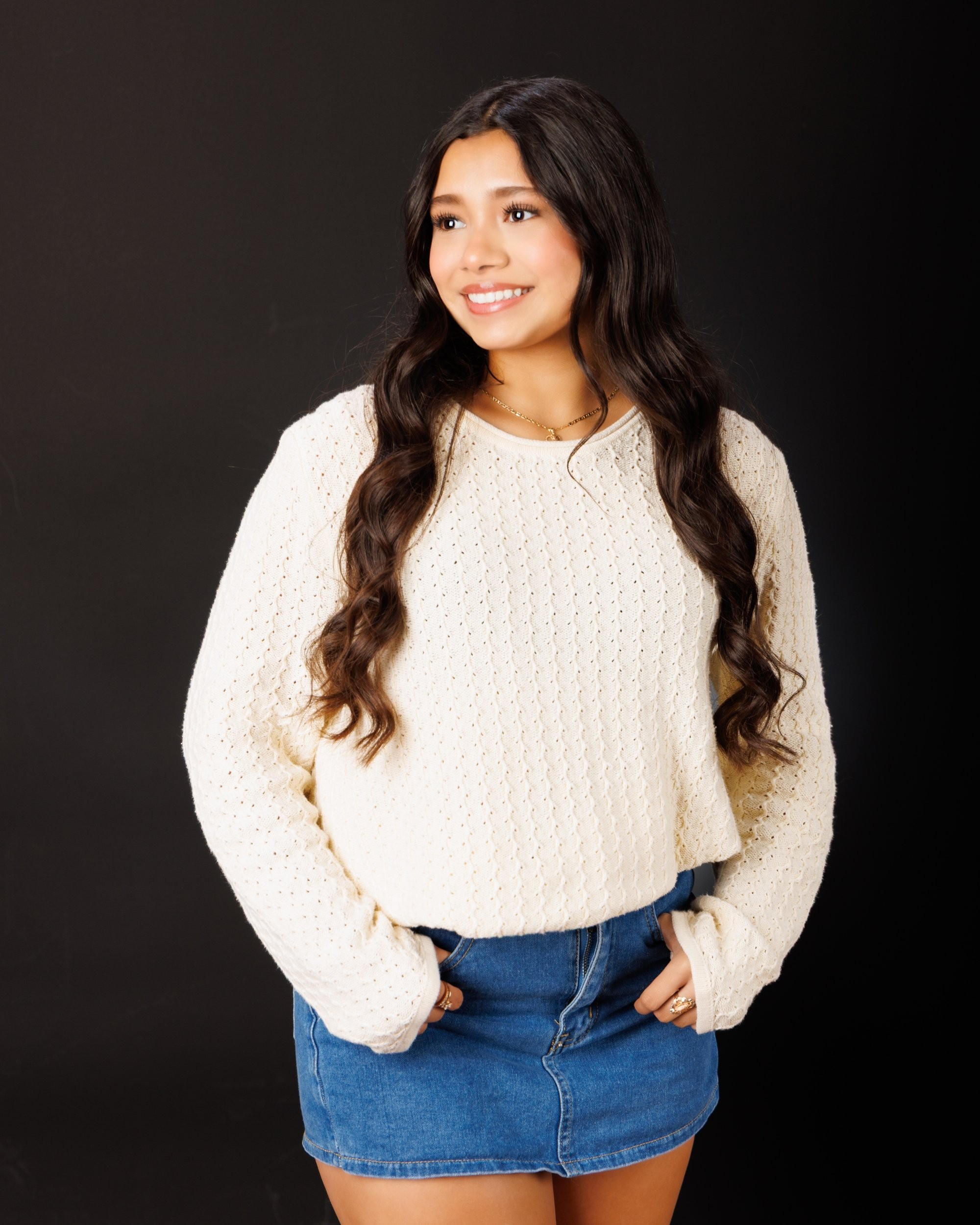 Maria in cream sweater with varsity jacket draped over shoulder