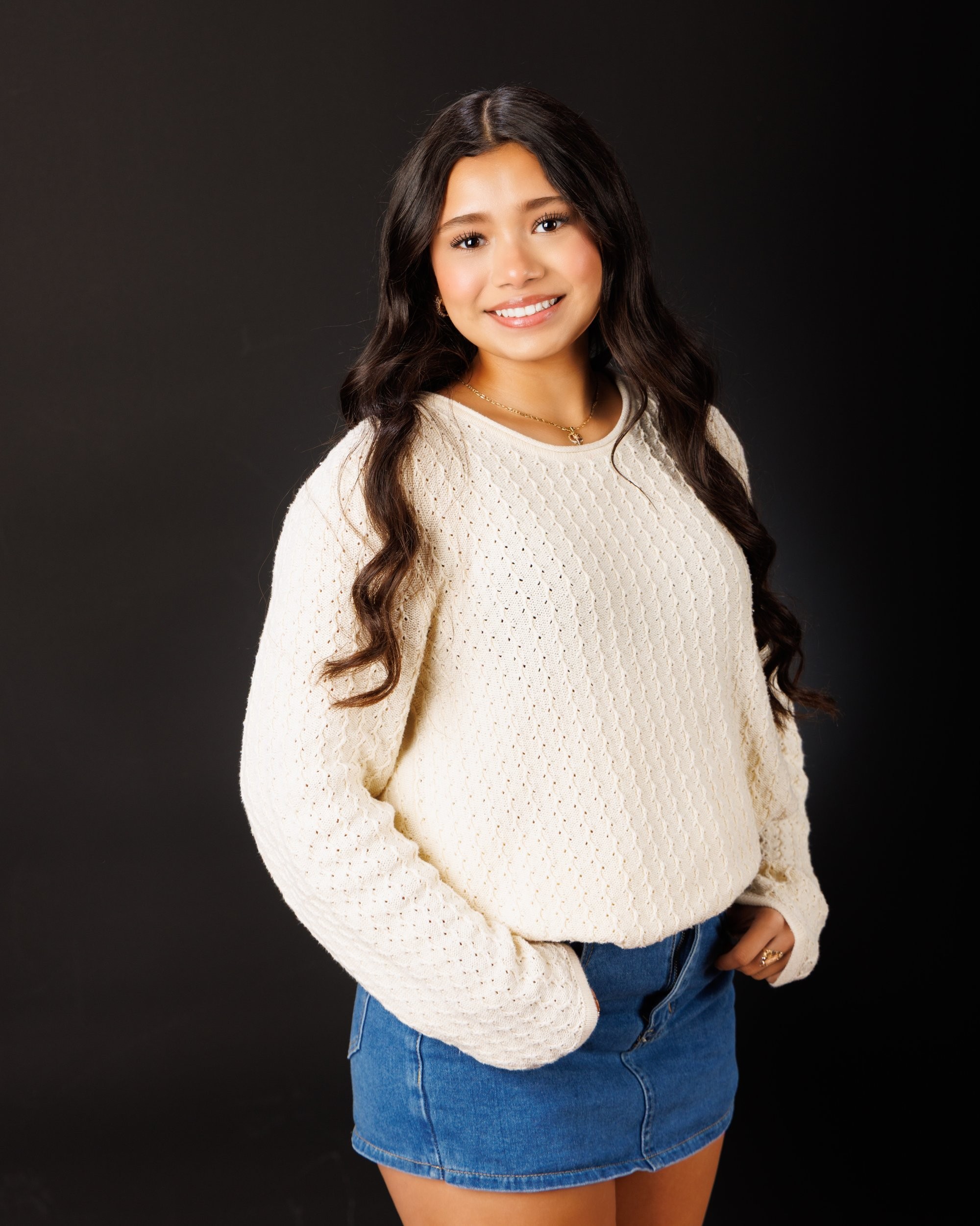 Maria in cream sweater with varsity jacket draped over shoulder