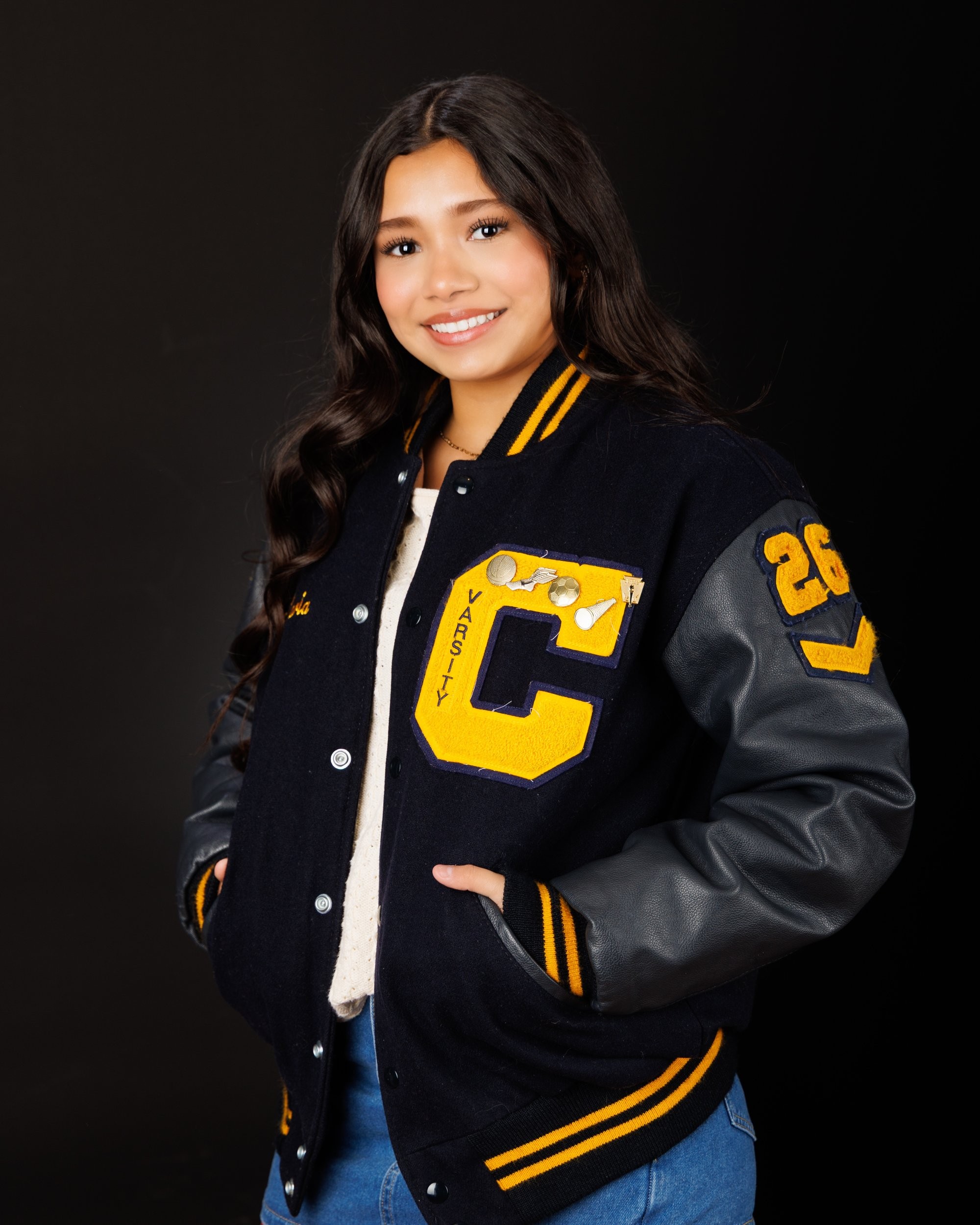 Maria in cream sweater with varsity jacket draped over shoulder